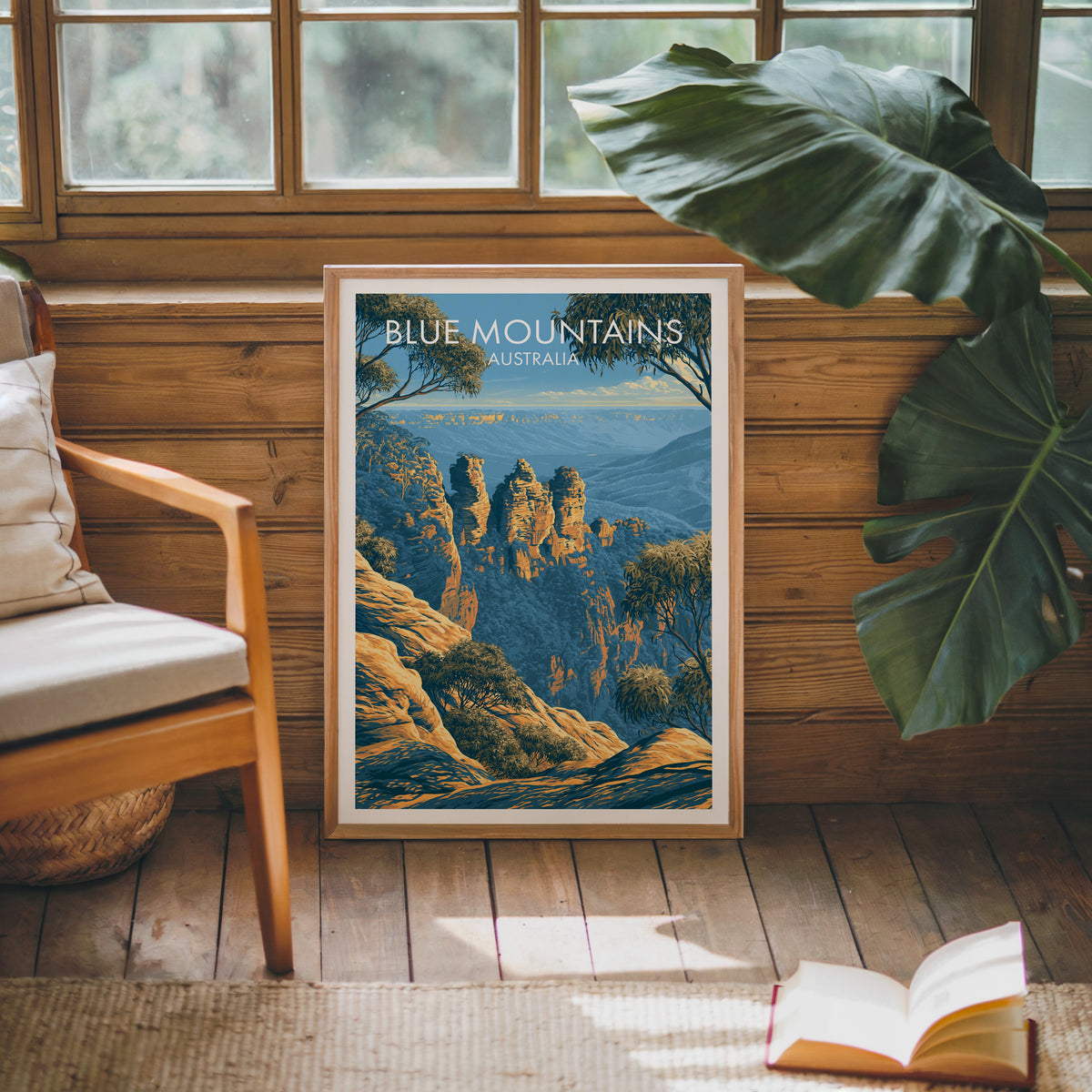 Australian escarpment artwork framed against a pine cabin wall with a monstera leaf and open book