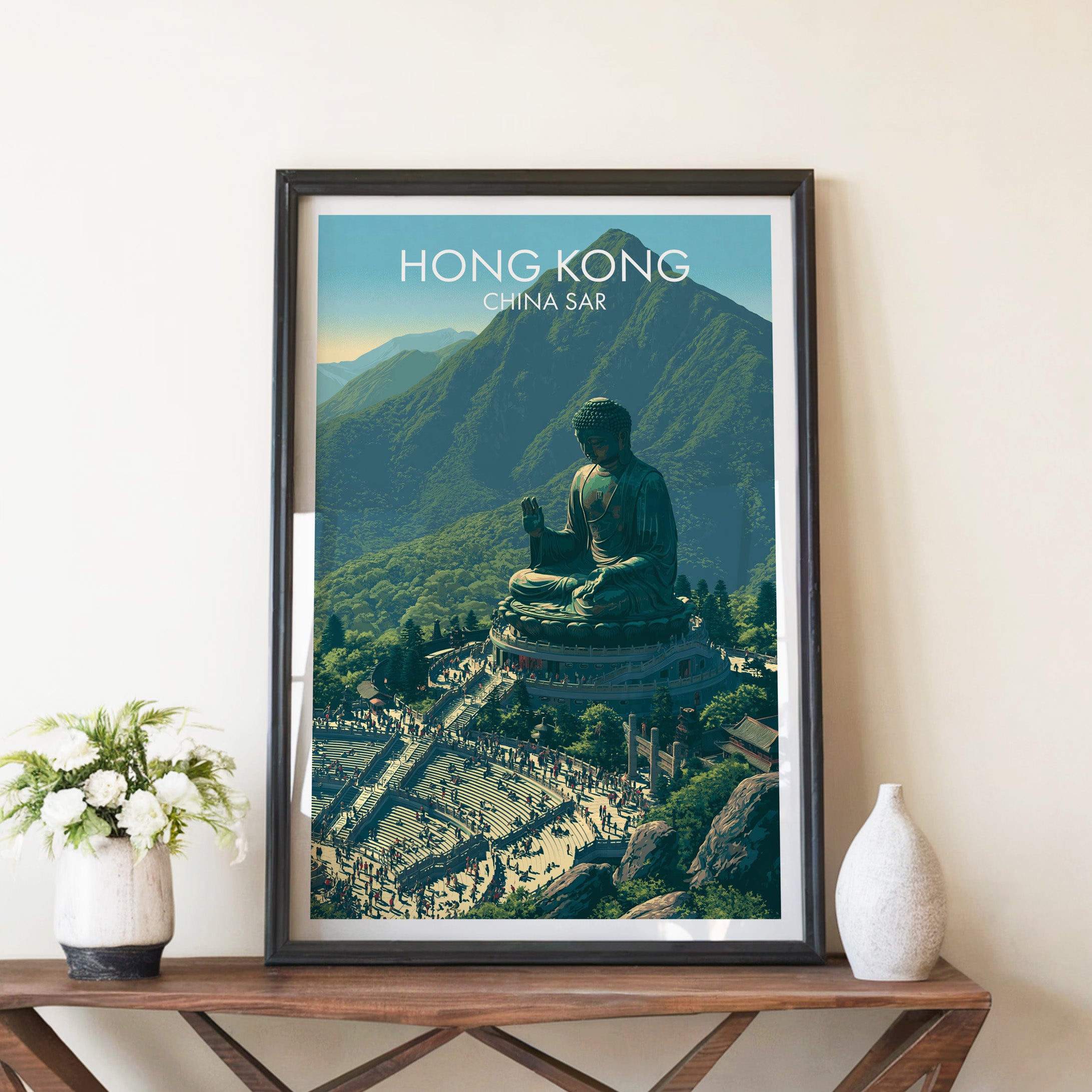 Tian Tan Big Buddha Hong Kong travel poster in a black frame on a wooden console table with white flowers