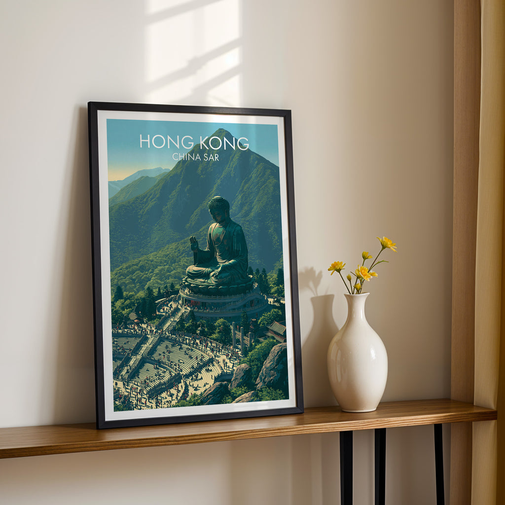 Black framed Tian Tan Big Buddha Hong Kong print on a narrow hallway console in sunlight, styled with yellow flowers