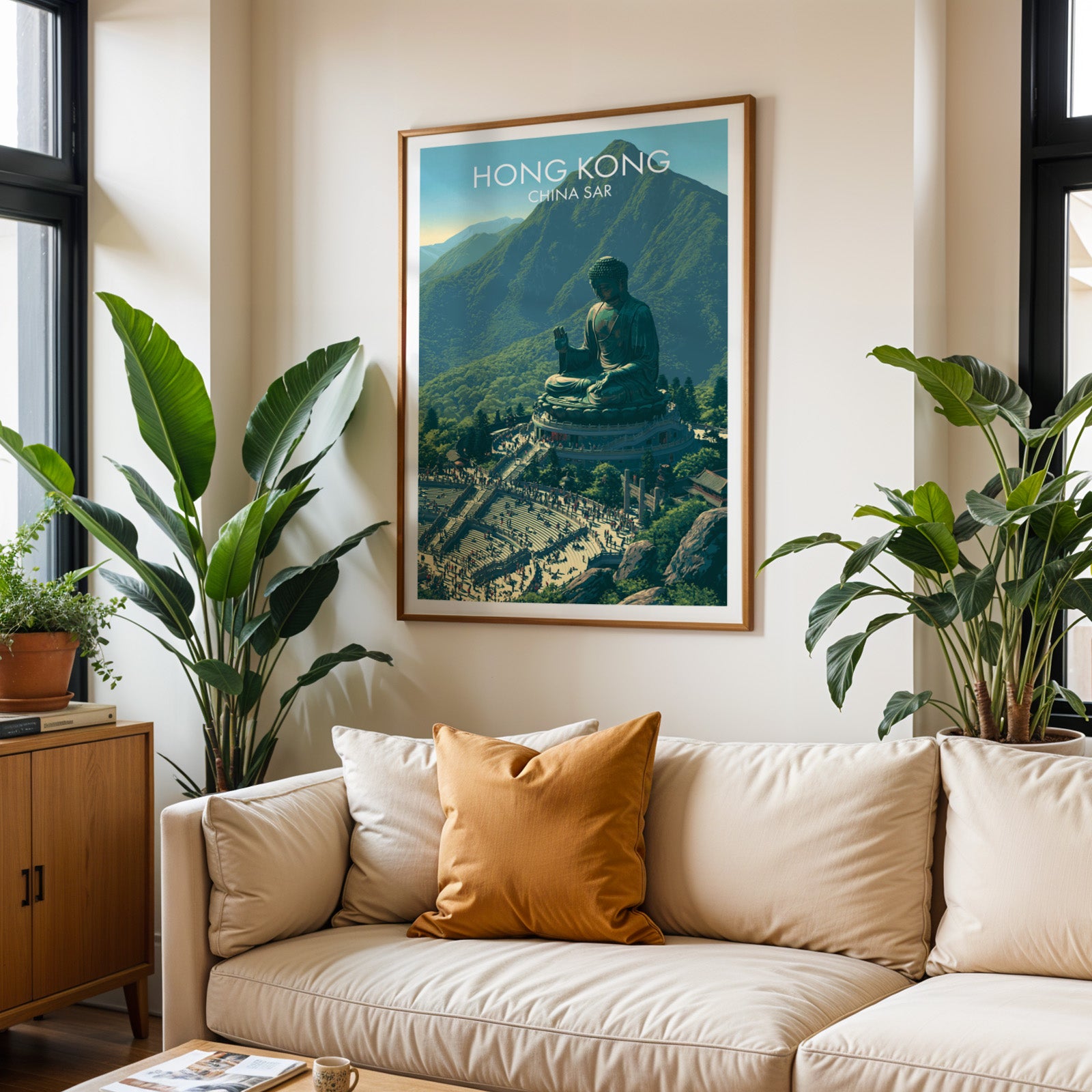 Framed Tian Tan Big Buddha Hong Kong wall art hanging above a cream sofa in a bright living room with tropical plants