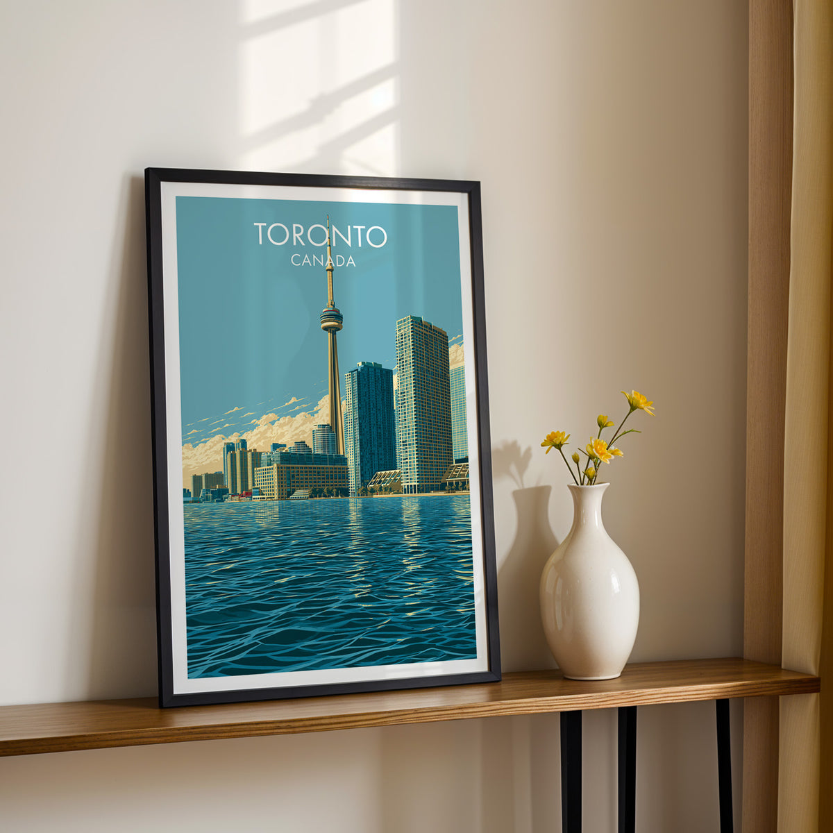 Toronto CN Tower sunset poster in a black frame on a sunlit shelf next to yellow daisies