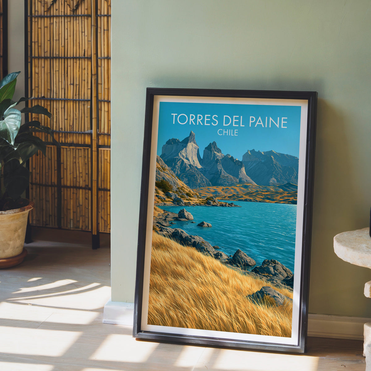 Paine horns print in a dark brown frame on a light wood floor by a sage wall, bamboo screen and terracotta planter