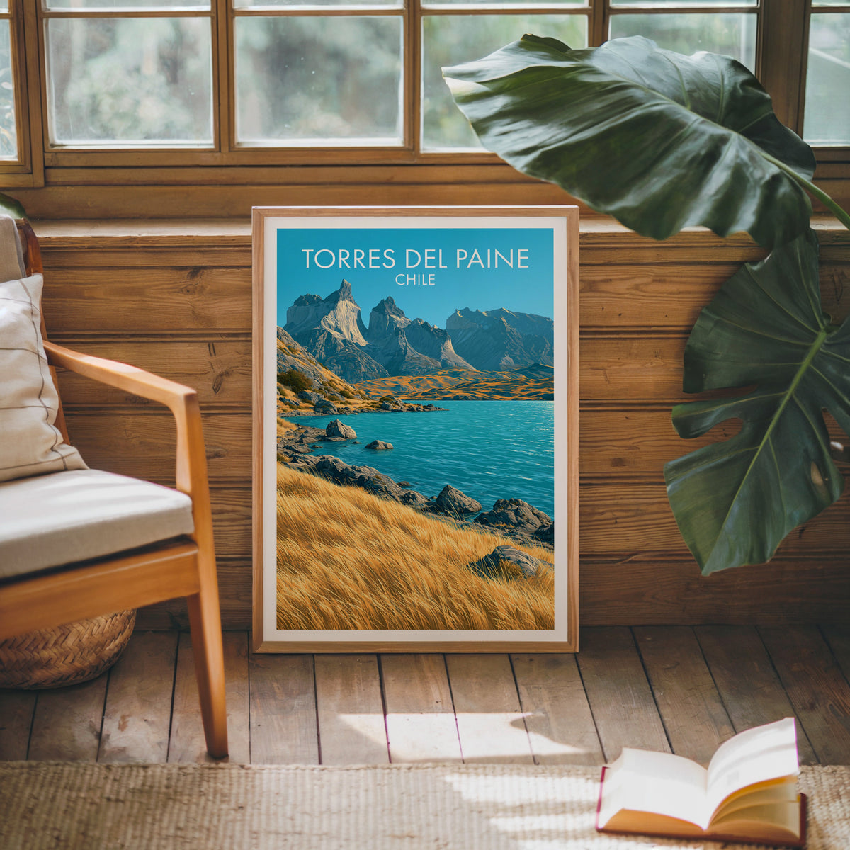 Torres del Paine poster in an oak frame on a pine cabin wall with a wood chair, cream cushion and monstera leaf