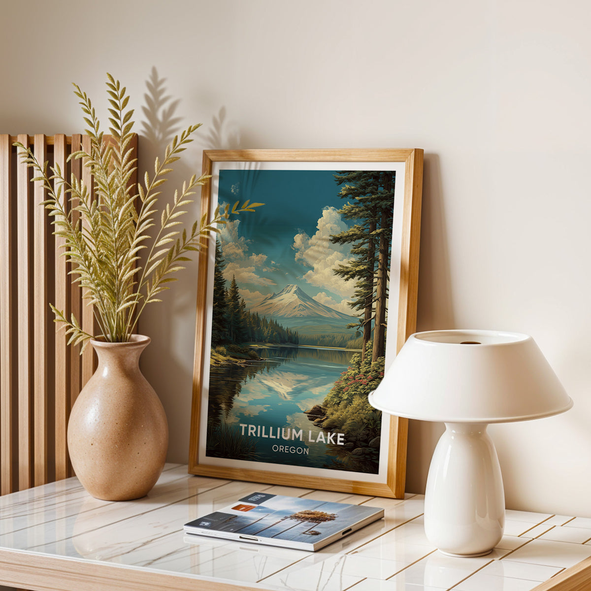 Mount Hood reflection print framed in oak on a stone table with dried leaves, a lamp and magazines.