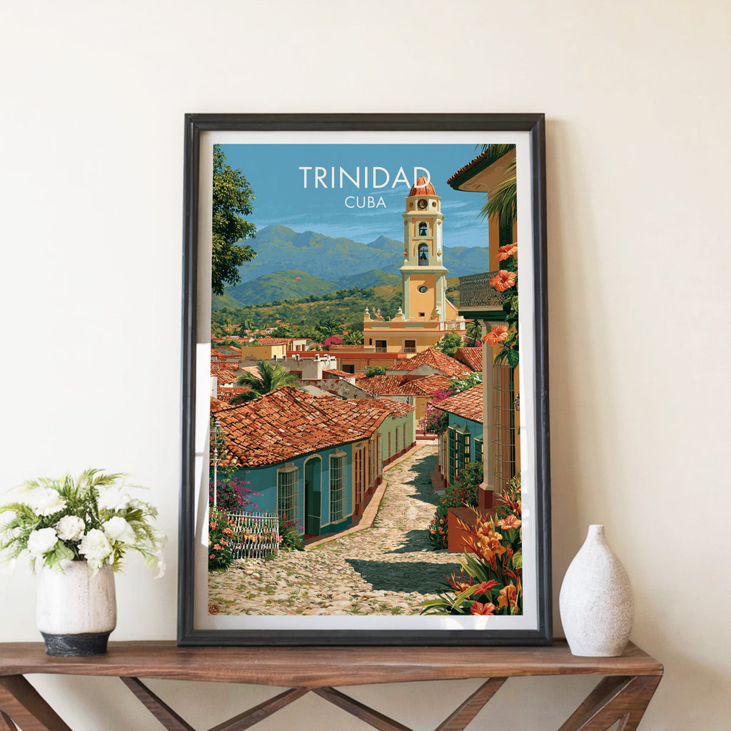 Yellow bell tower over Trinidad in a black frame on a walnut console with white peonies and a white ceramic vase