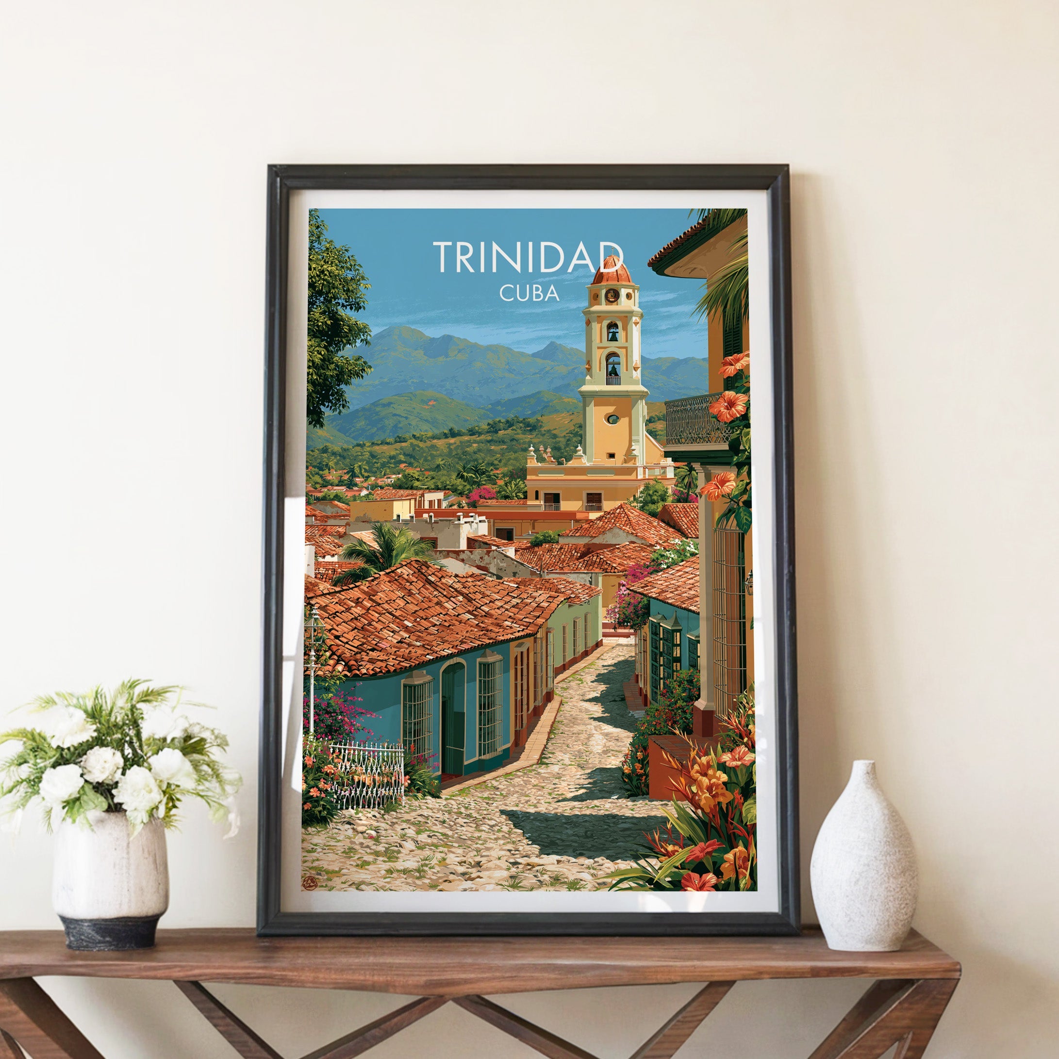 Yellow bell tower over Trinidad in a black frame on a walnut console with white peonies and a white ceramic vase