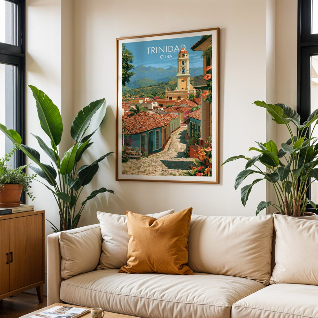 Cuban hill town poster in an oak frame above a cream sofa with a burnt-orange cushion and two tropical plants