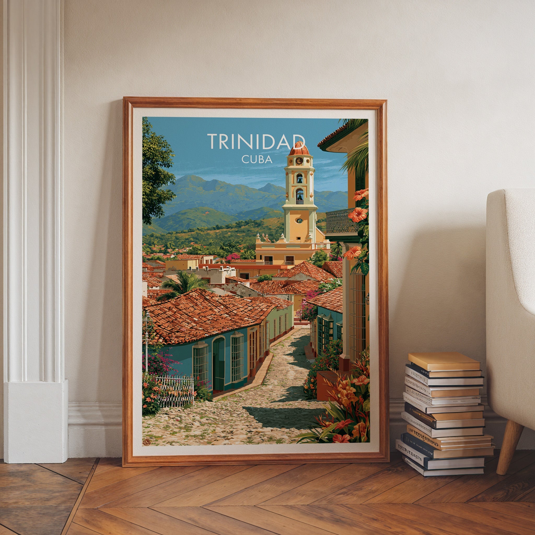 Cuba travel print of red-tiled roofs in a walnut frame on herringbone floor with stacked books and an armchair