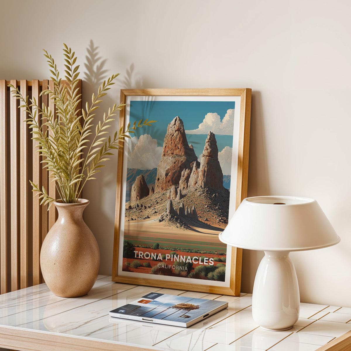 California desert print framed in oak on a stone table with dried stems, magazines and a domed lamp.