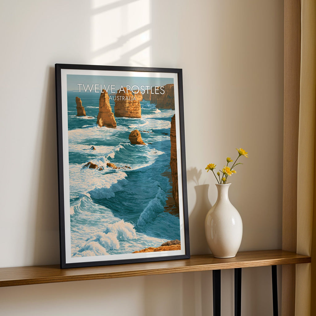 Twelve Apostles artwork in a black frame on a wood shelf with yellow daisies against a sunlit cream wall