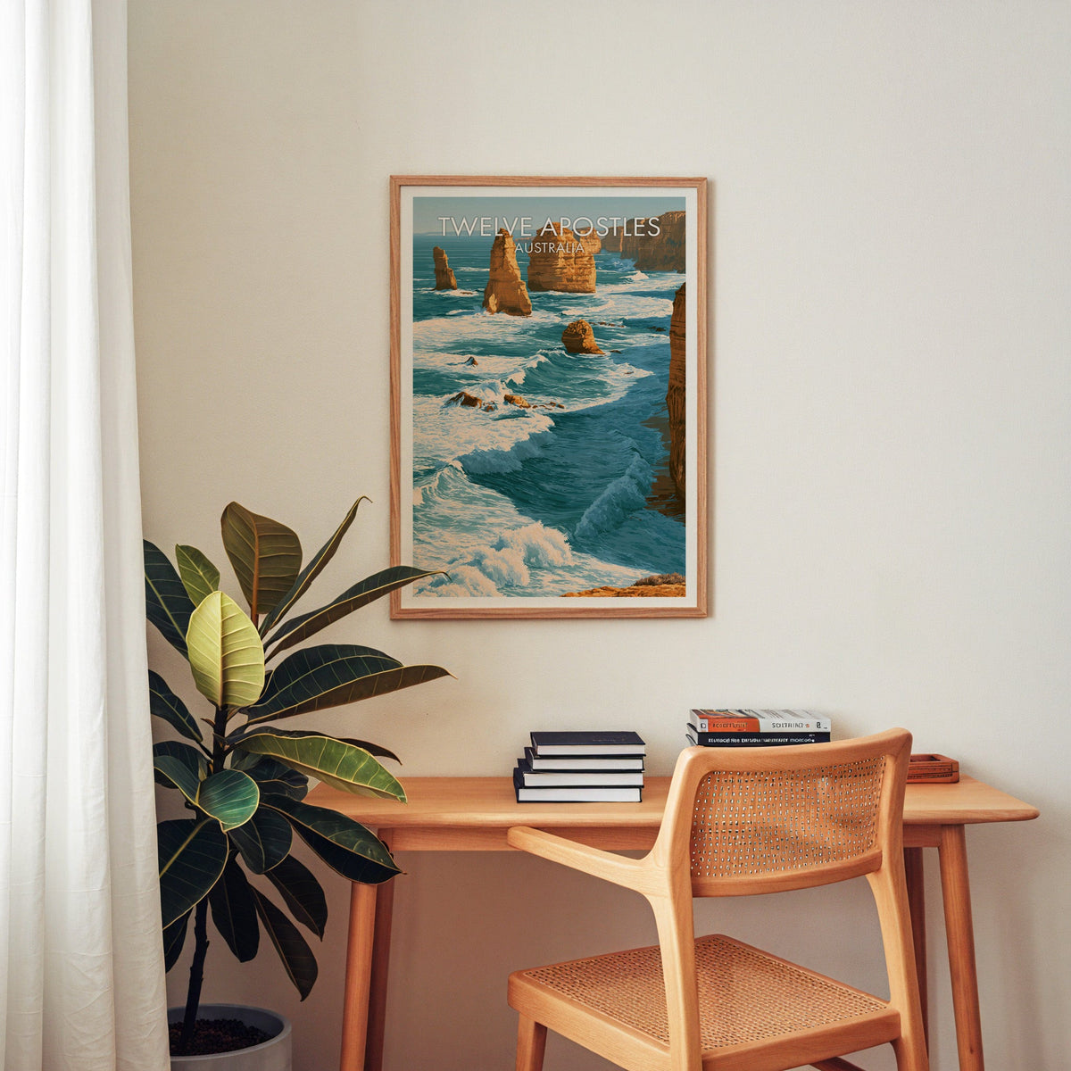 Sea stacks poster in an oak frame above a wooden home office desk with a cane chair and stacked books
