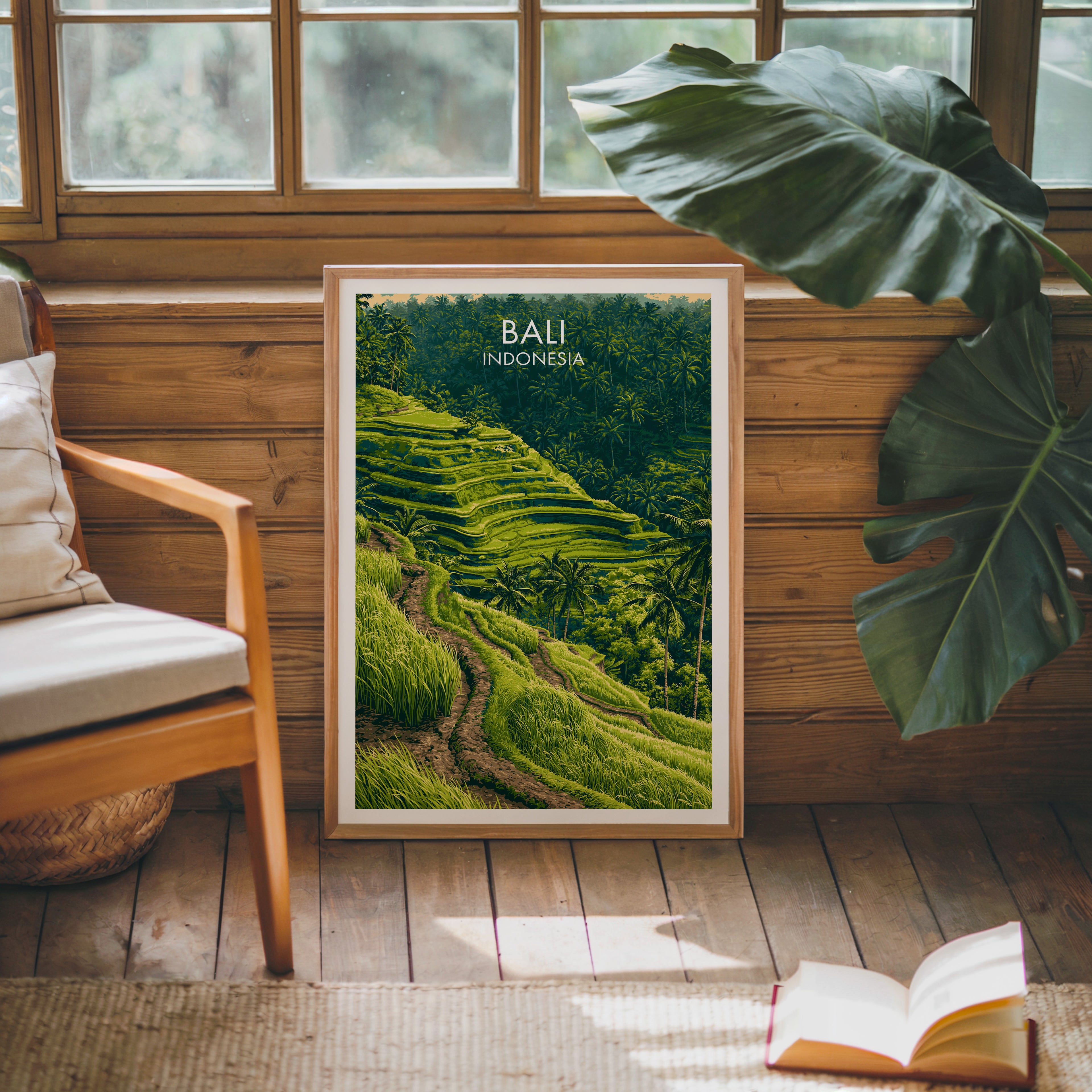 Framed Ubud Rice Terraces Bali poster leaning against a timber cabin wall with monstera leaves and an open book