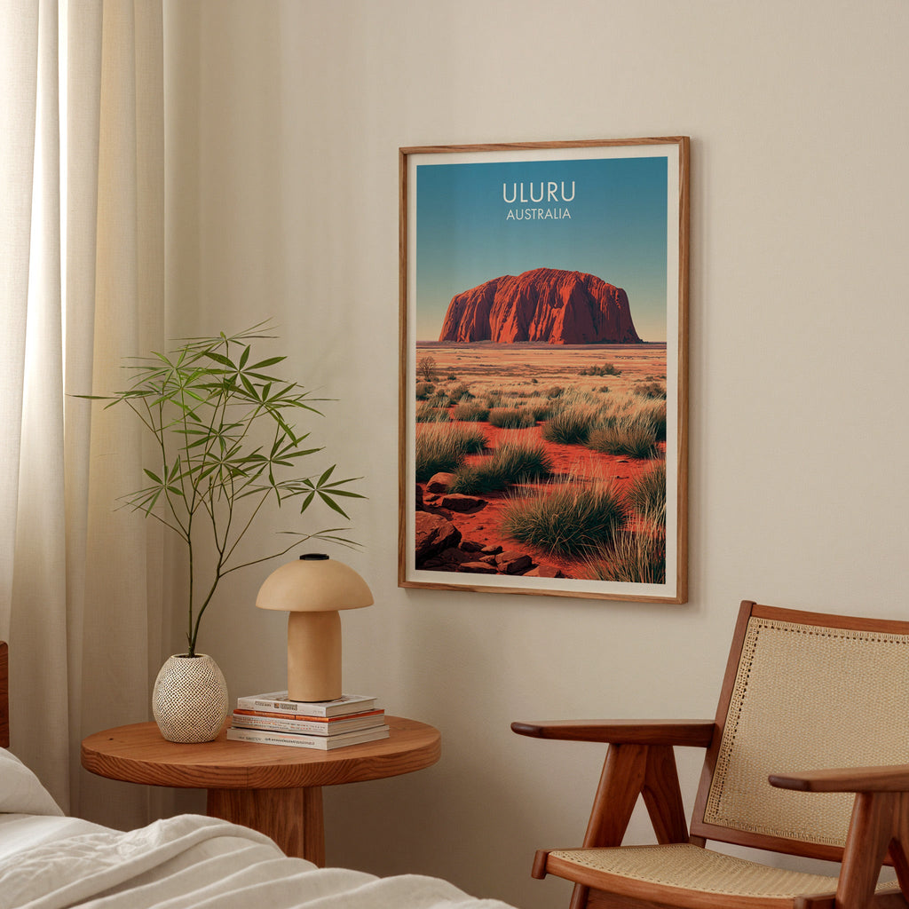 Framed red desert print in a bedroom above a bedside table with a mushroom lamp and cane armchair