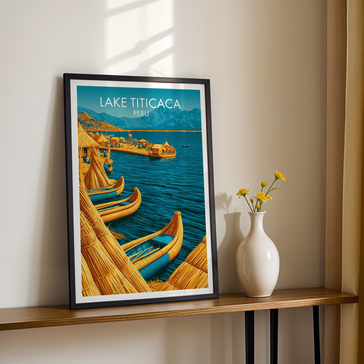 Floating island wall art in a black frame on a narrow wood shelf beside yellow daisies in a white vase