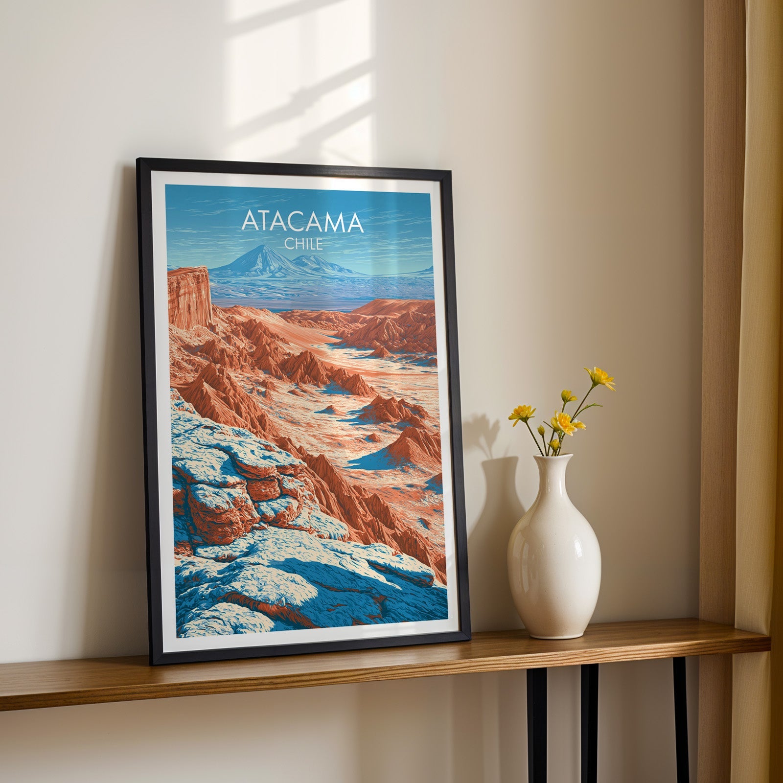 Moon Valley wall art in a black frame on a narrow wood shelf with black iron legs and yellow daisies in sunlight