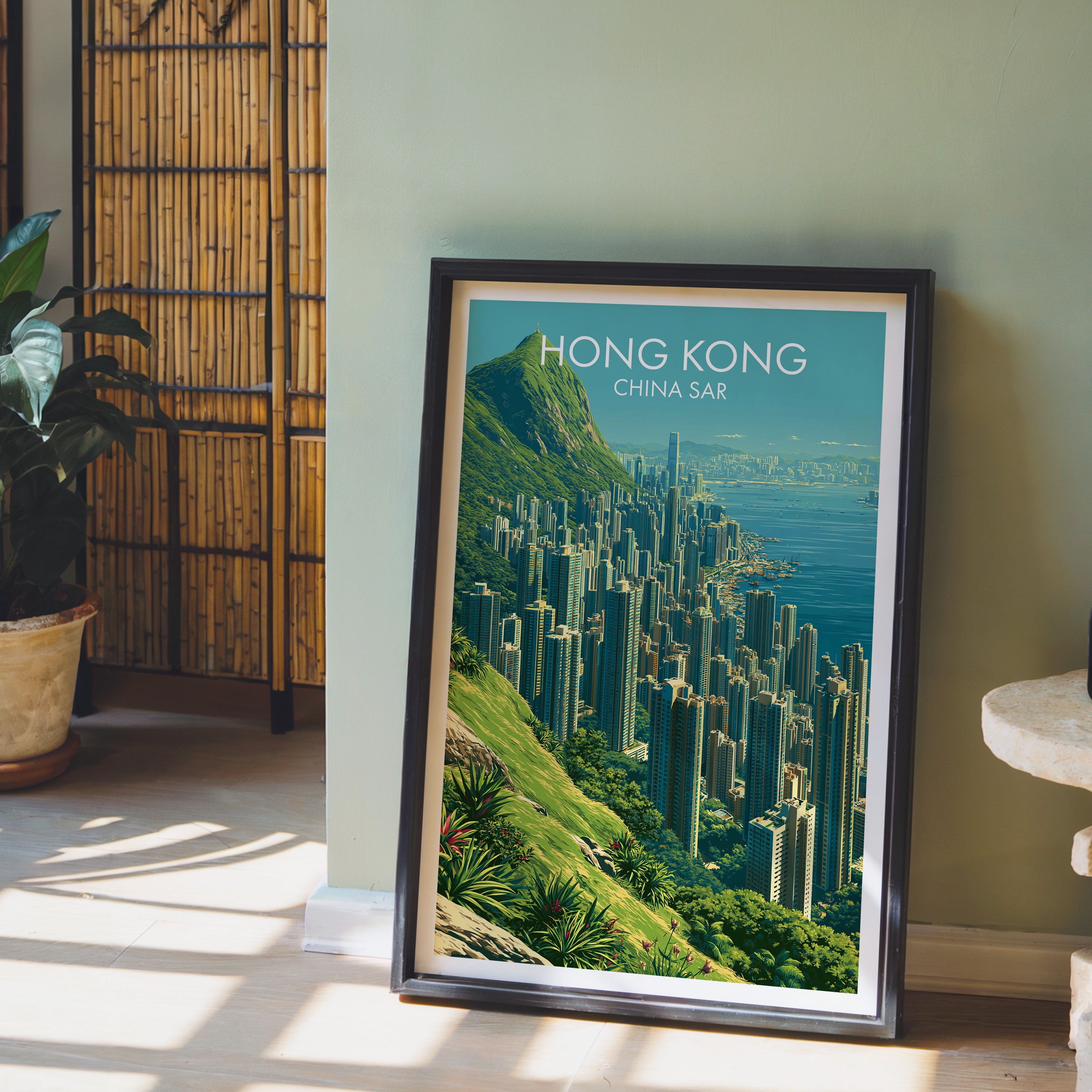 Victoria Peak Hong Kong wall art in a black frame leaning against a sage green wall beside a bamboo screen