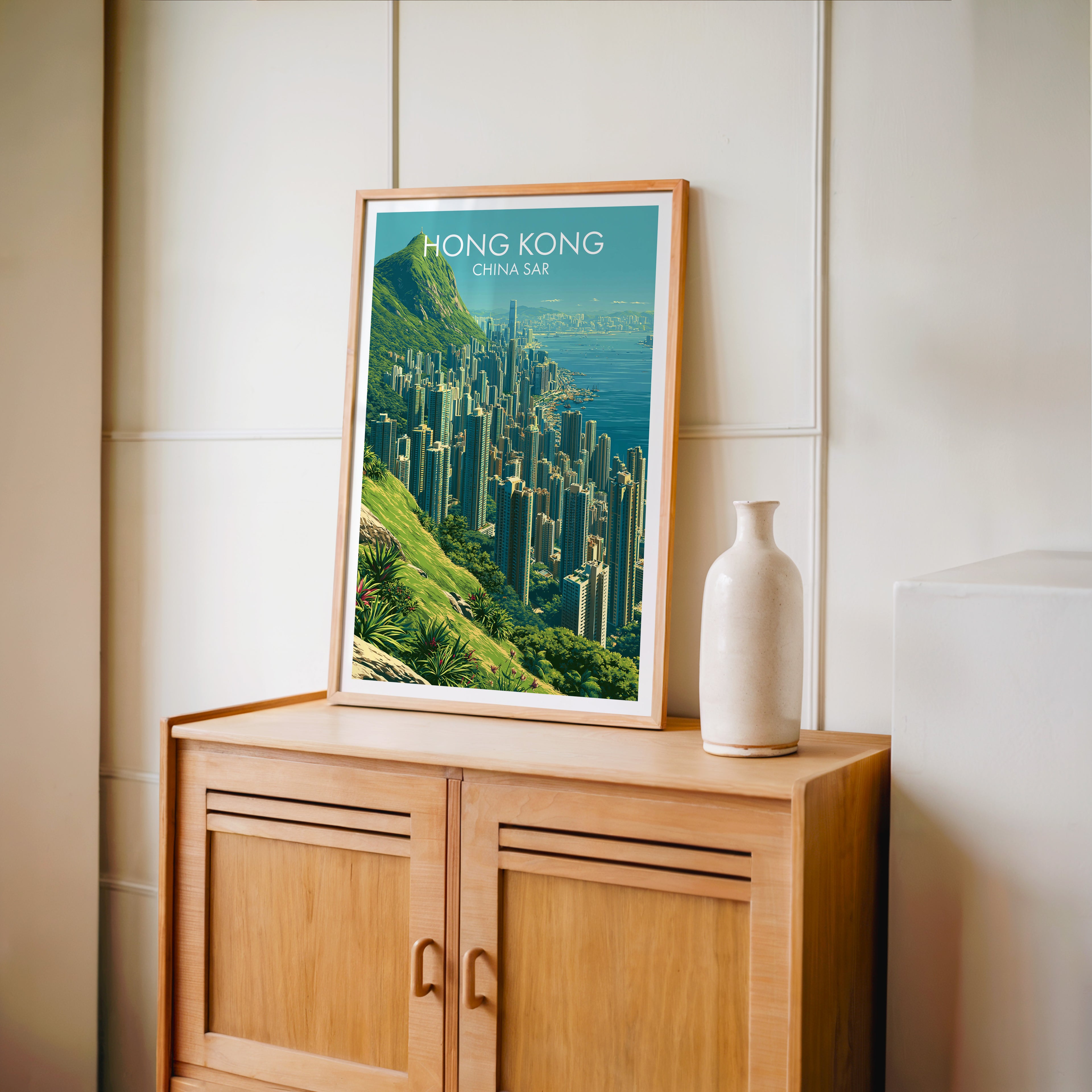Small Victoria Peak Hong Kong travel poster in an oak frame on a mid-century sideboard with a ceramic vase