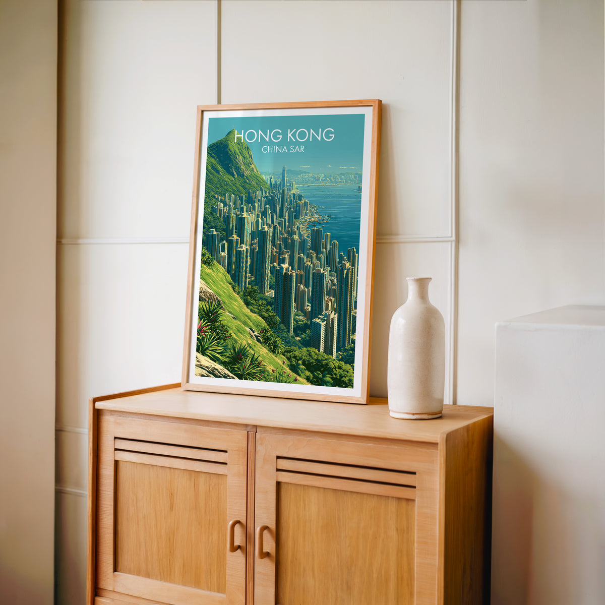 Victoria Peak Hong Kong travel poster in an oak frame standing on a light oak cabinet against a cream panelled wall