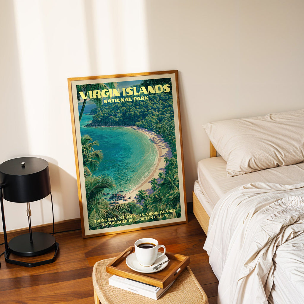 Trunk Bay Virgin Islands print in a gold frame on the floor beside a made bed and a black table lamp