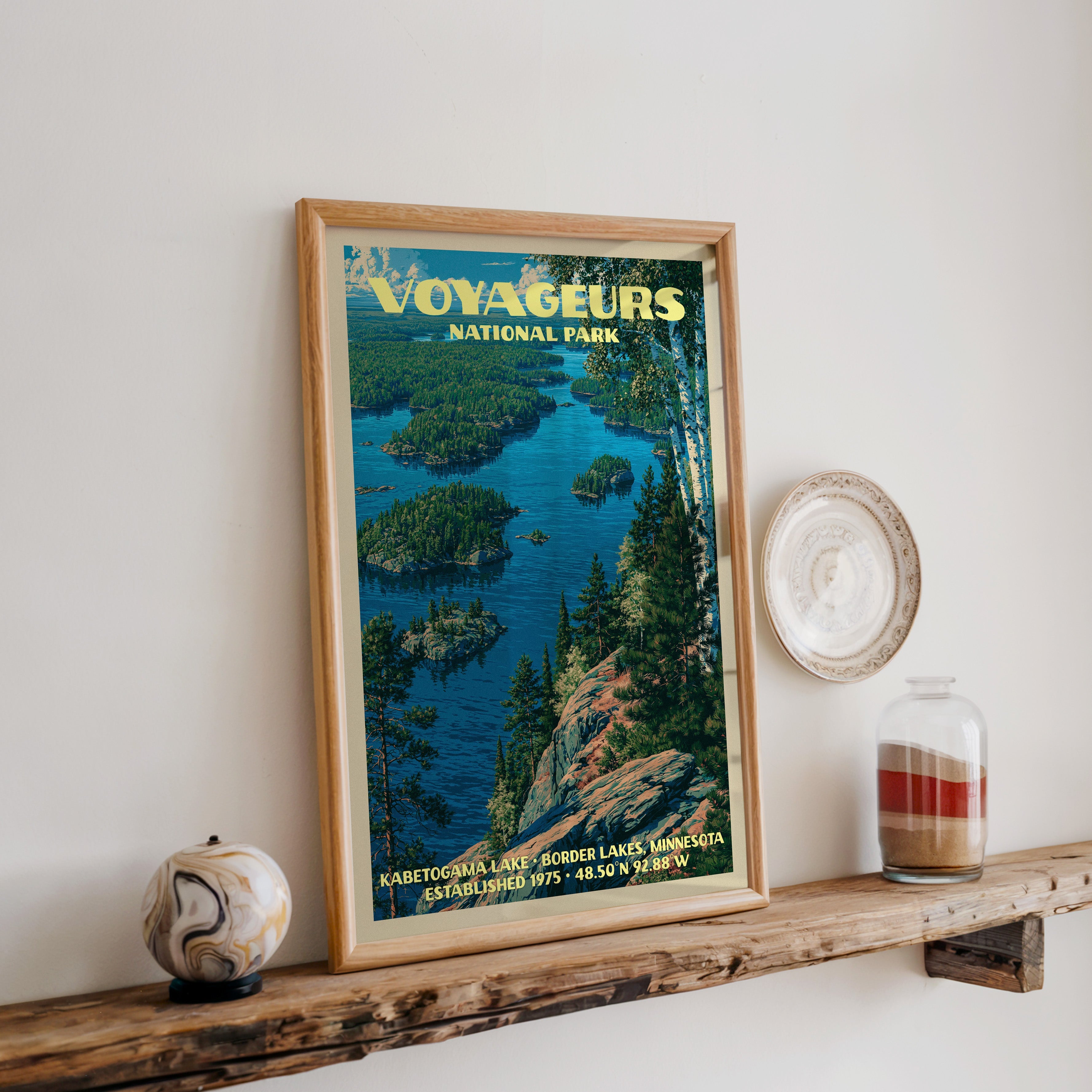 Voyageurs Kabetogama Lake print in oak, leaning on a reclaimed wood ledge with a stone sphere and sand jar