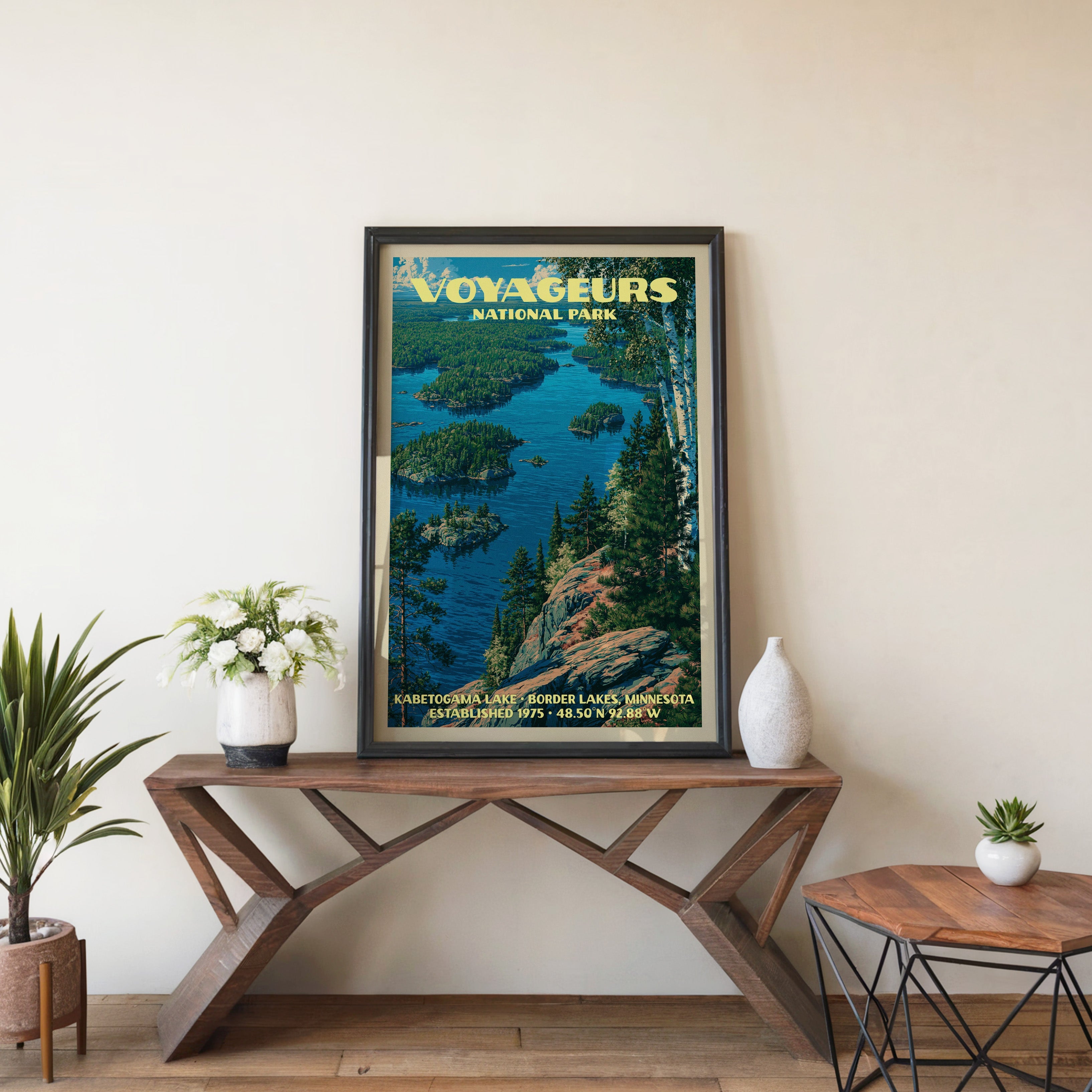 Kabetogama Lake wall art in black, leaning on a walnut console with white anemones and a small vase