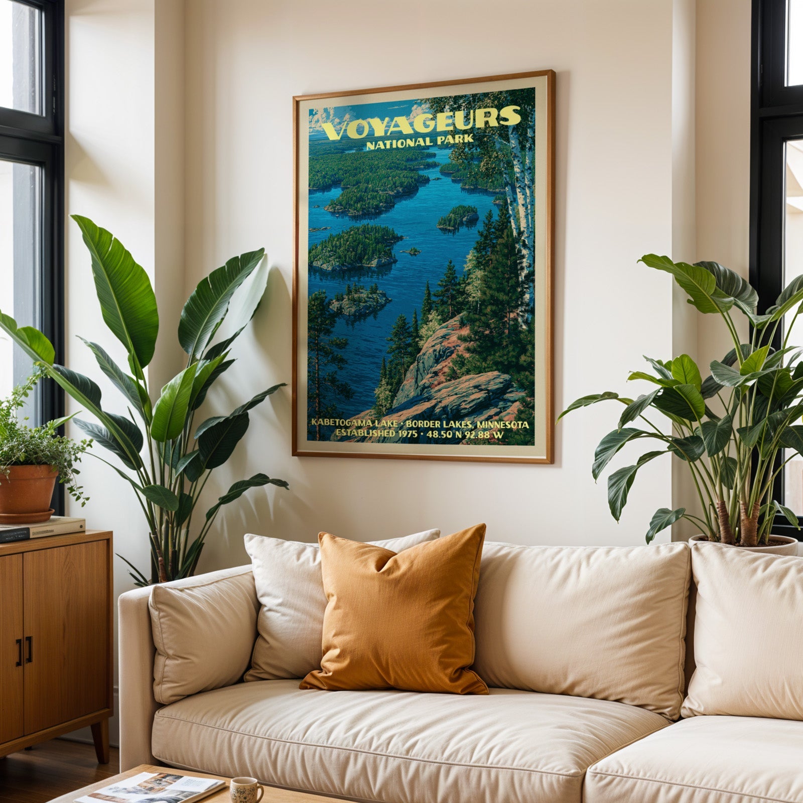 Voyageurs vintage travel print in oak above a cream sofa with a rust cushion and tall houseplants
