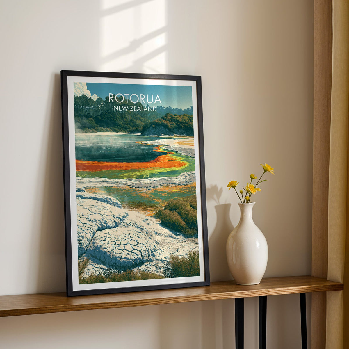 Orange mineral terrace artwork in a black frame on a wood shelf with yellow daisies on a cream wall