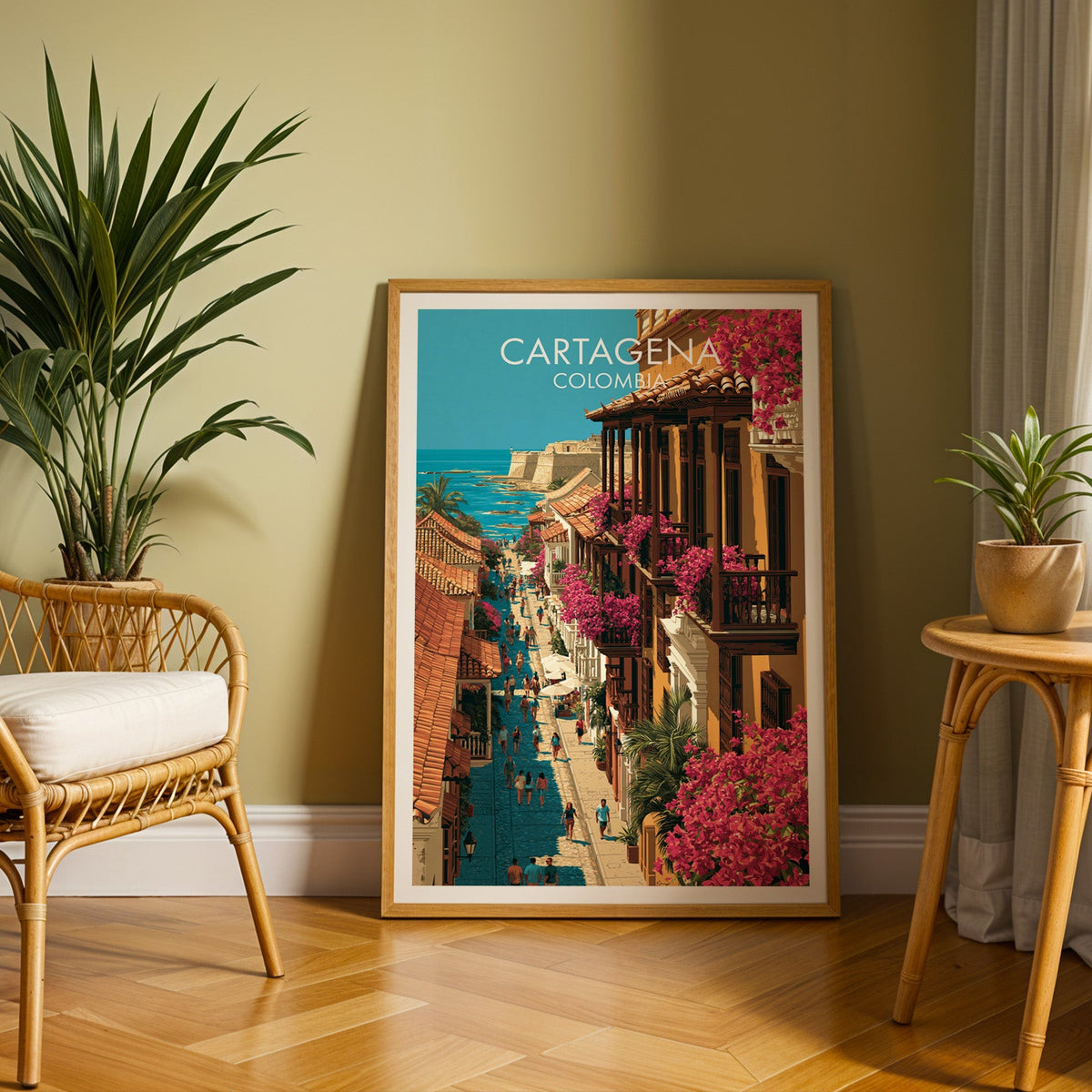 Colombian coastal town print in an oak frame on a herringbone floor by an olive wall with a rattan chair and palm