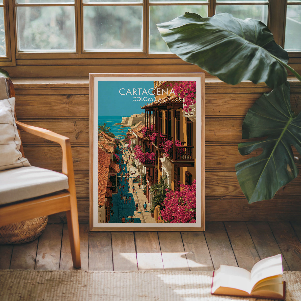 Ochre facades print in an oak frame on a pine cabin wall beside a cream cushioned chair, monstera leaf and book
