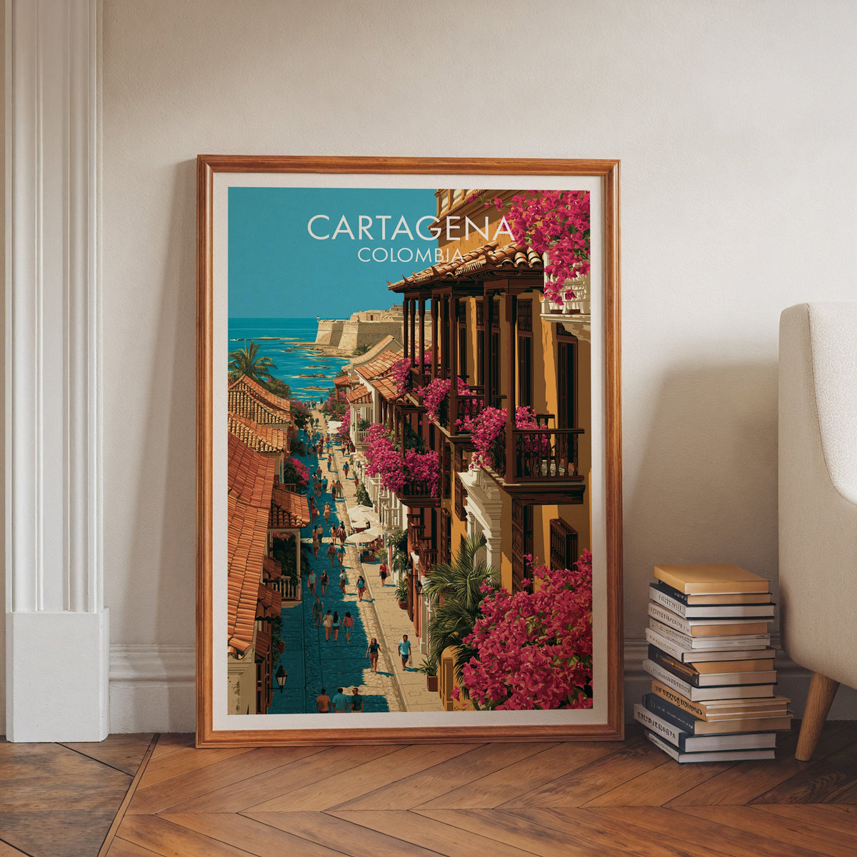 Cartagena old town print in a walnut frame on a herringbone floor by white wall moulding and a cream armchair