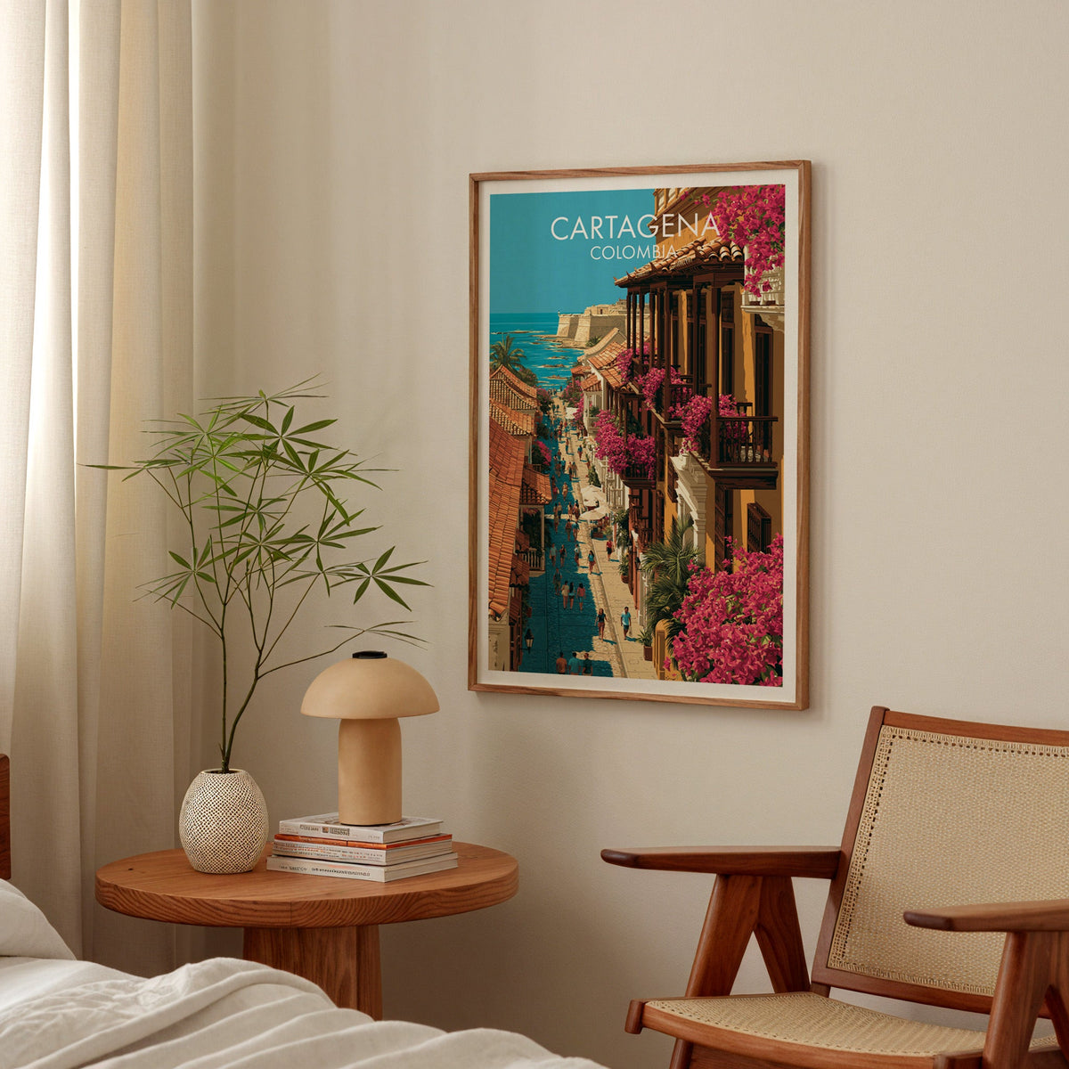 Cobbled lane and sea wall art in a walnut frame in a bedroom above a round nightstand with a terracotta lamp