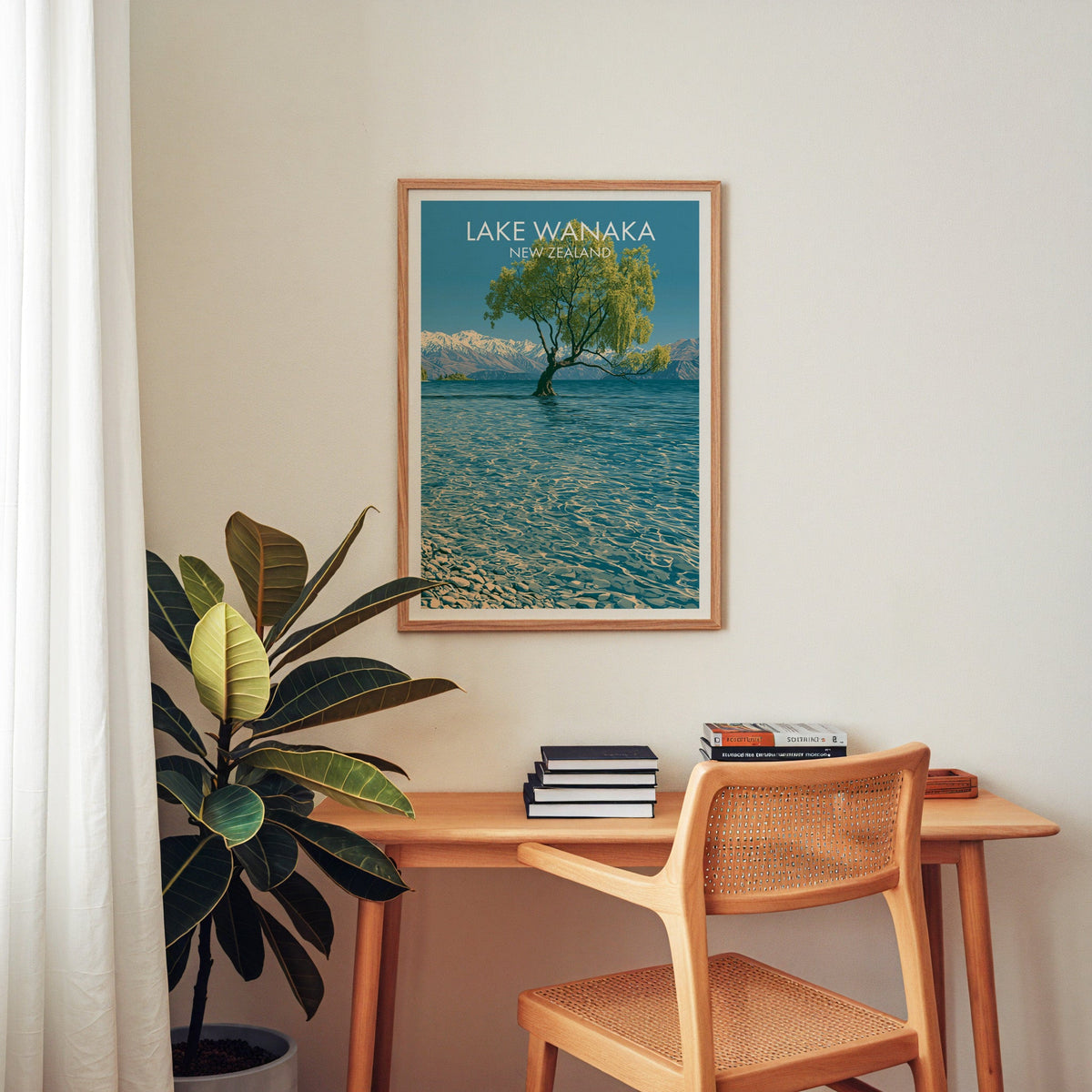 Lake Wanaka travel poster above a wooden home-office desk with a cane chair and a rubber plant