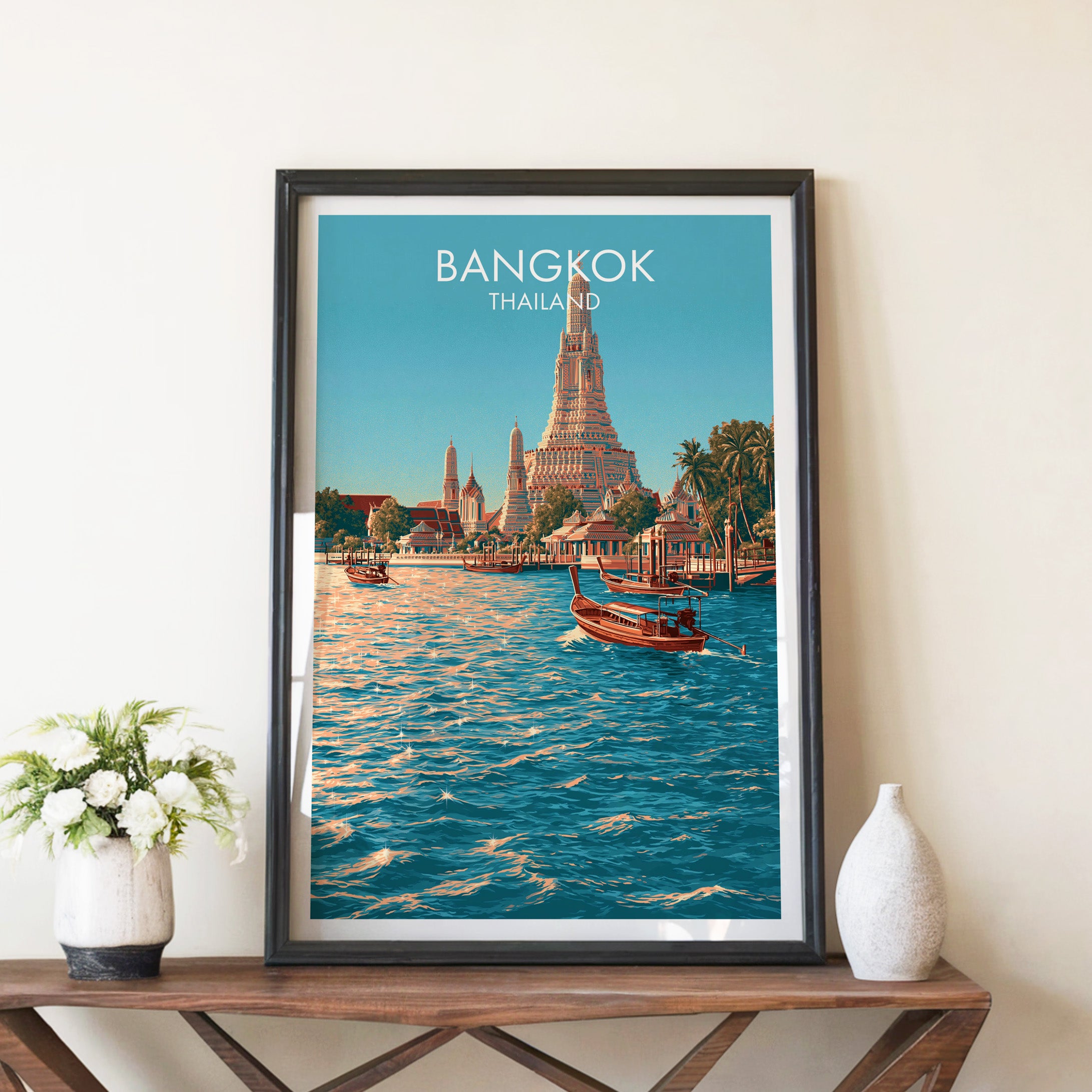 Wat Arun Bangkok Thailand travel poster in a black frame on a wooden console table with white flowers
