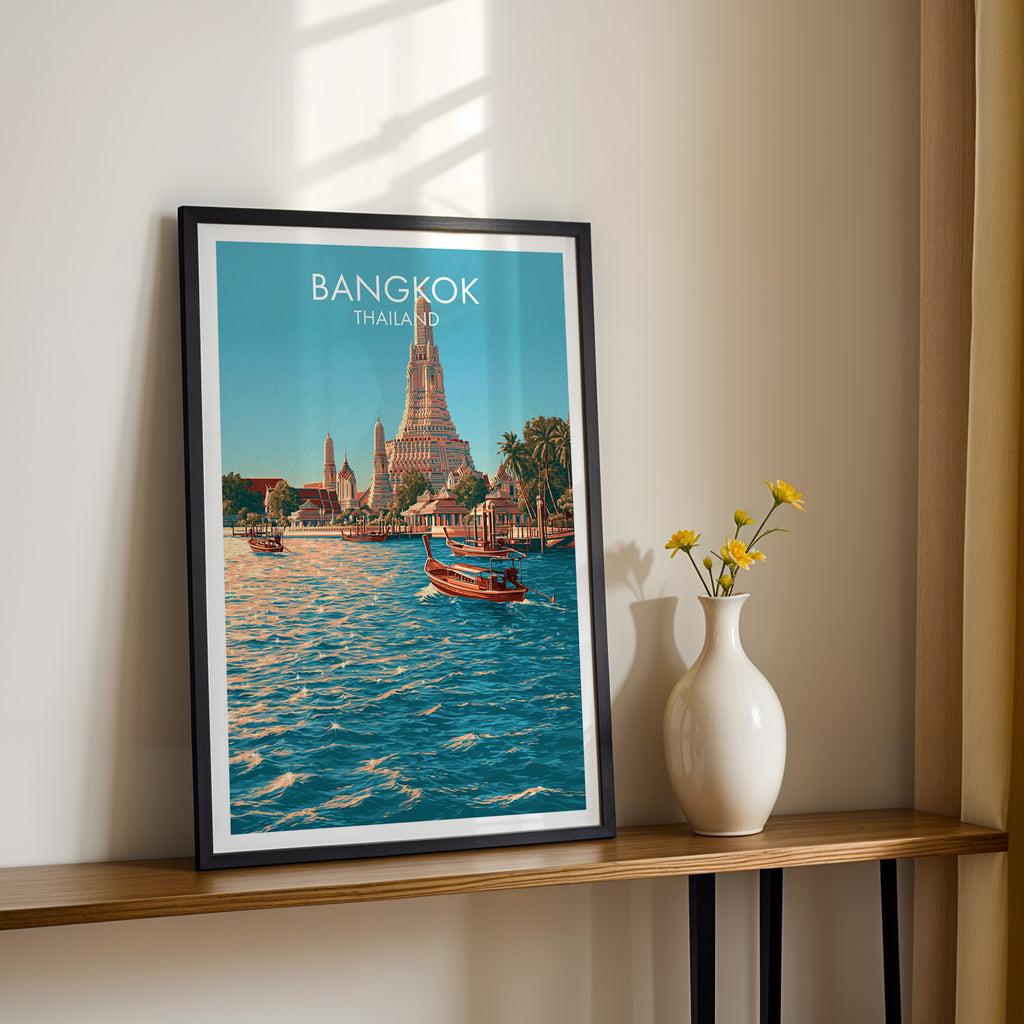 Black framed Wat Arun Bangkok Thailand print on a narrow hallway console in sunlight, styled with yellow flowers