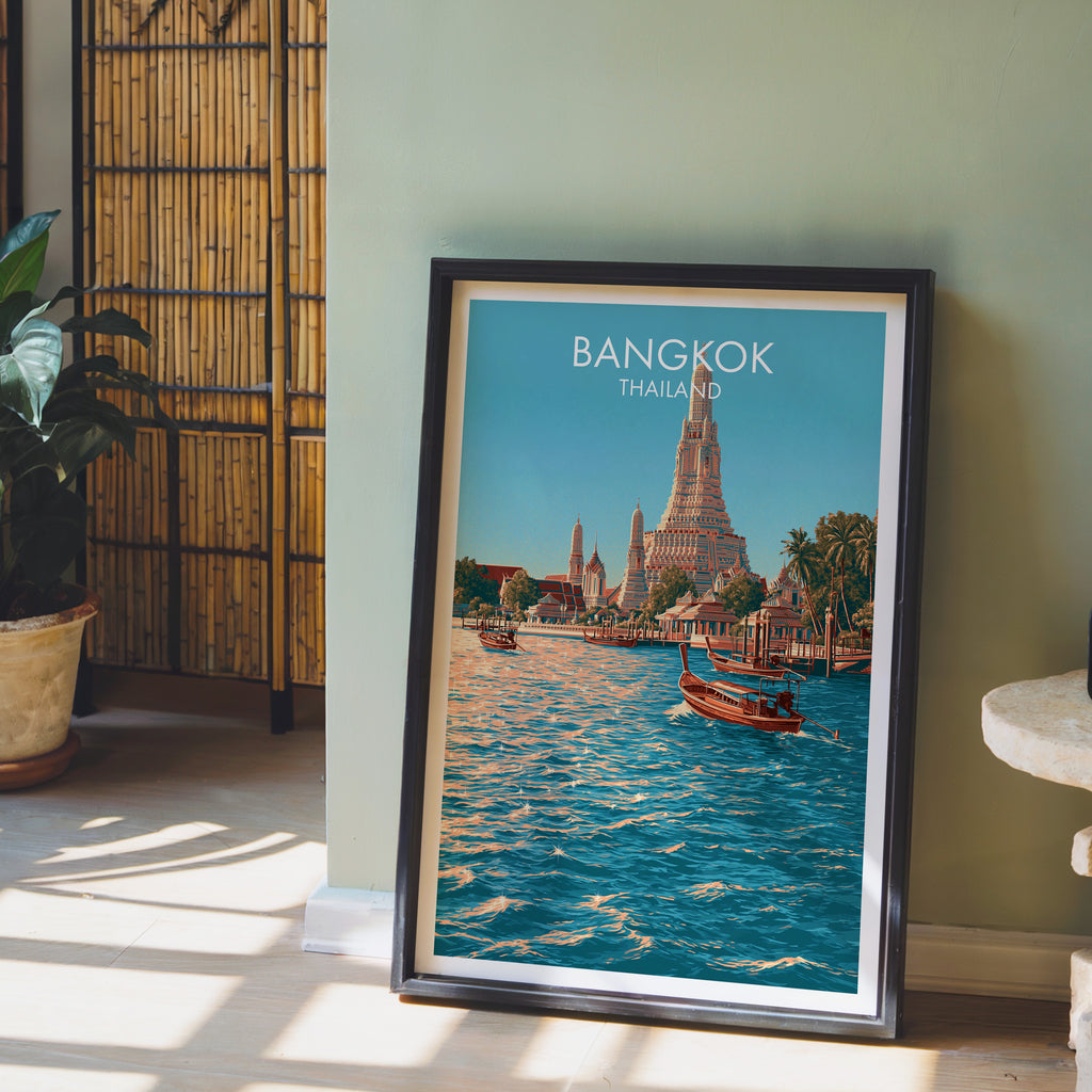 Wat Arun Bangkok Thailand wall art in a black frame leaning against a sage green wall beside a bamboo screen