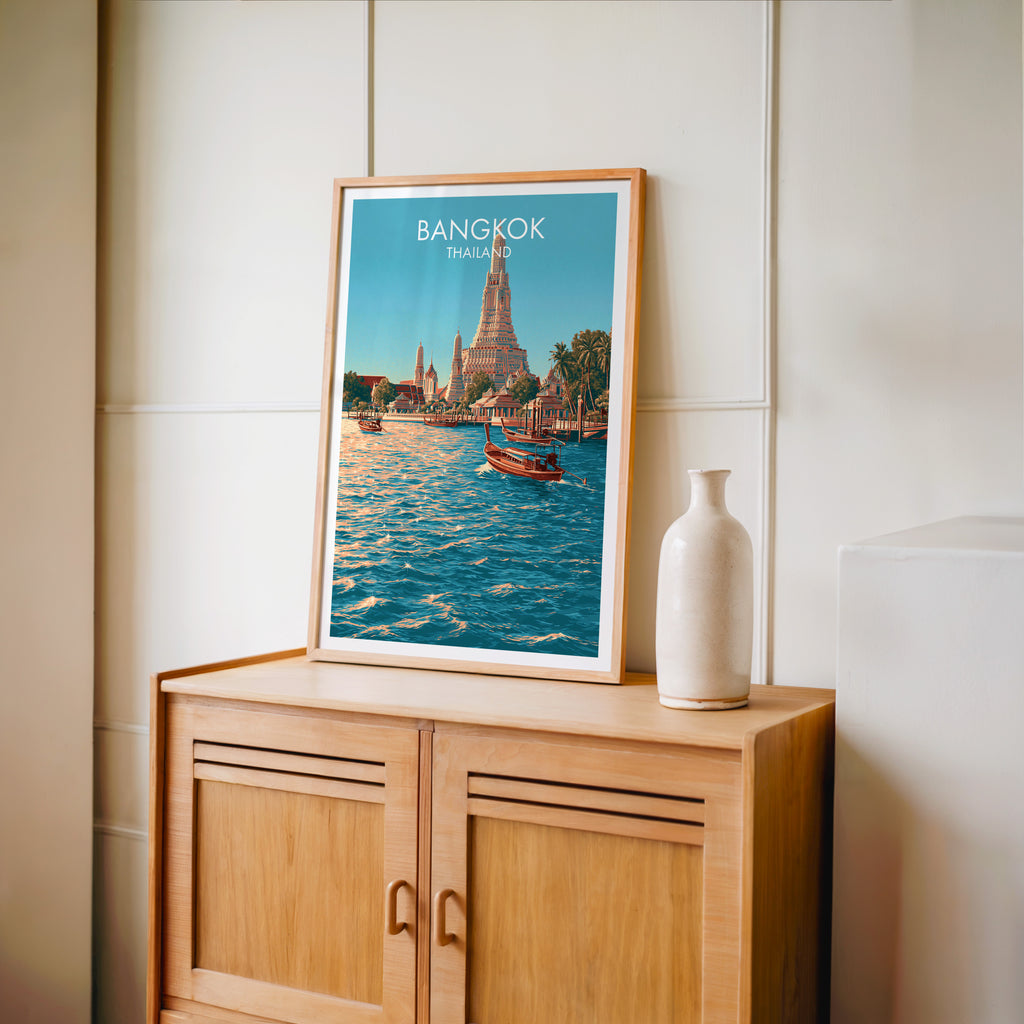 Small Wat Arun Bangkok Thailand travel poster in an oak frame on a mid-century sideboard with a ceramic vase