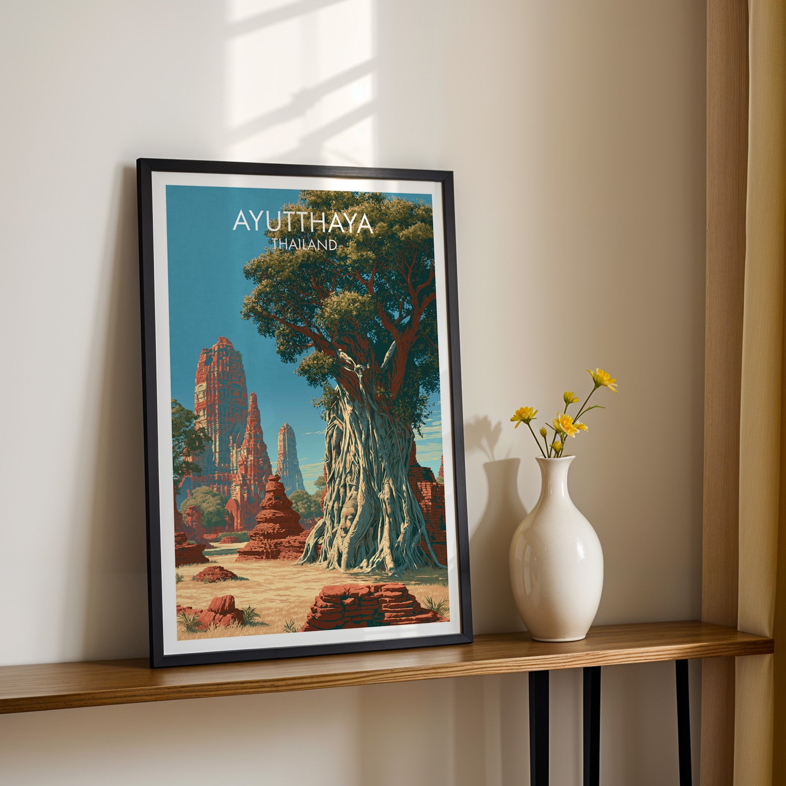 Black framed Wat Mahathat Ayutthaya Thailand print on a narrow hallway console in sunlight, styled with yellow flowers