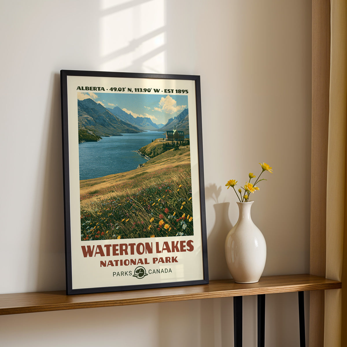 Waterton lake and hotel wall art in a black frame on a sunlit shelf next to yellow daisies