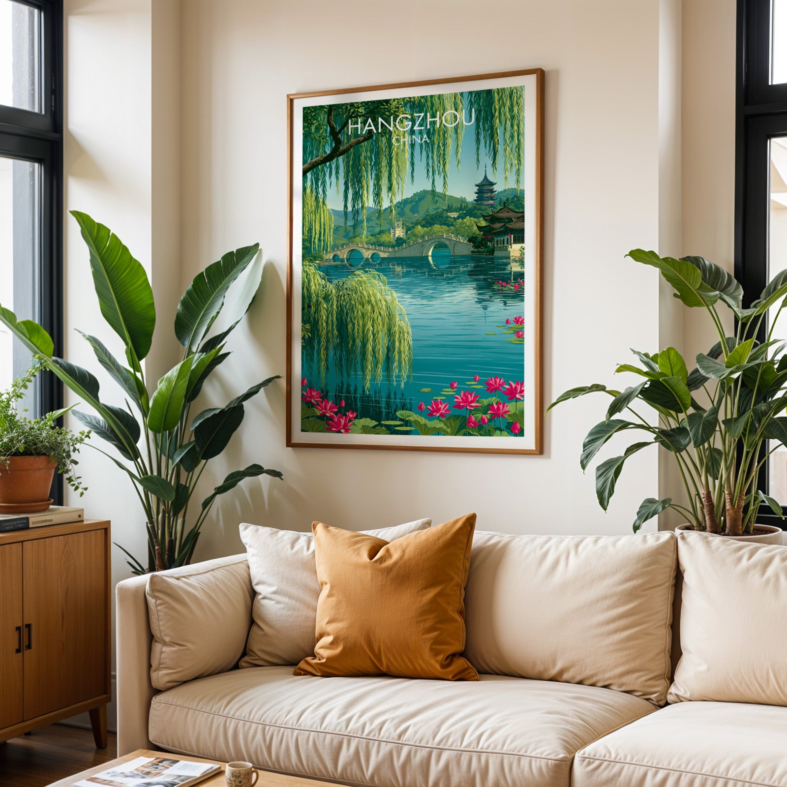 Framed West Lake Hangzhou China wall art hanging above a cream sofa in a bright living room with tropical plants