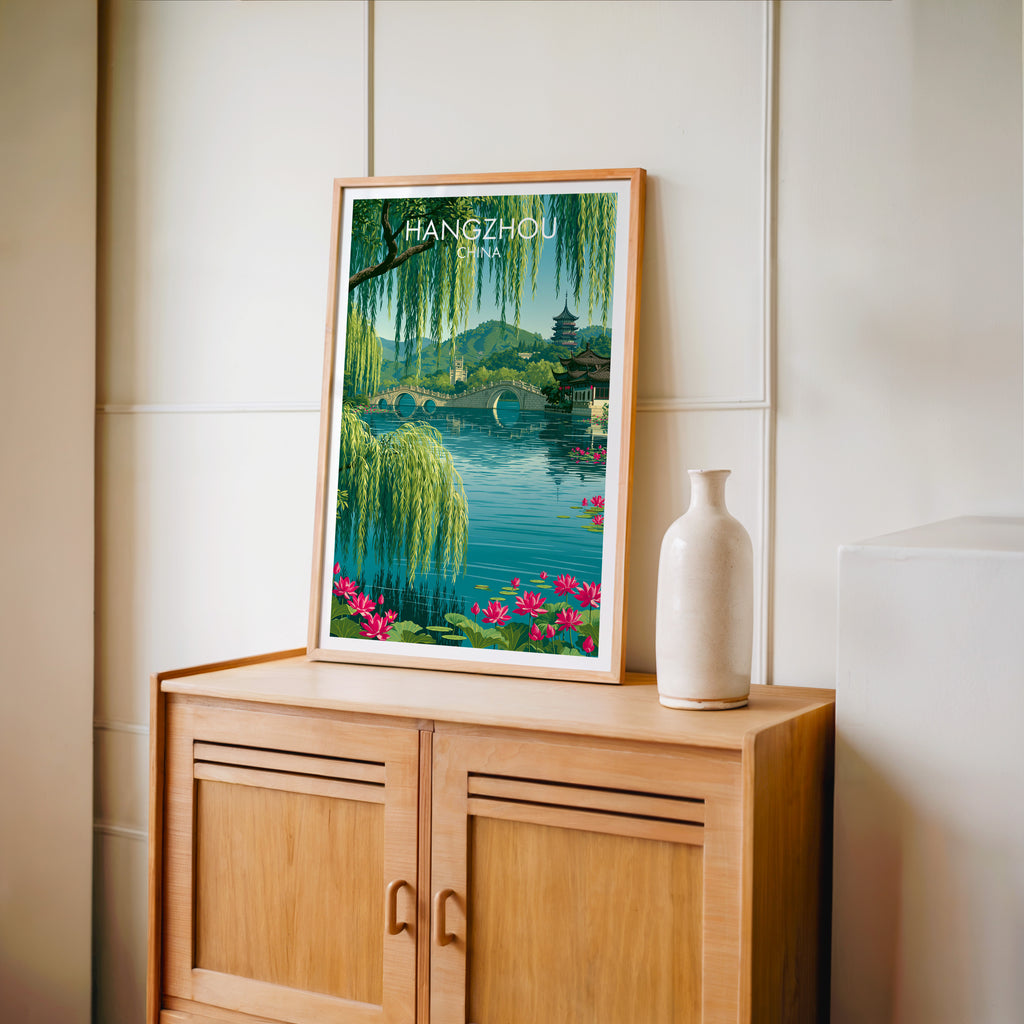 Small West Lake Hangzhou China travel poster in an oak frame on a mid-century sideboard with a ceramic vase