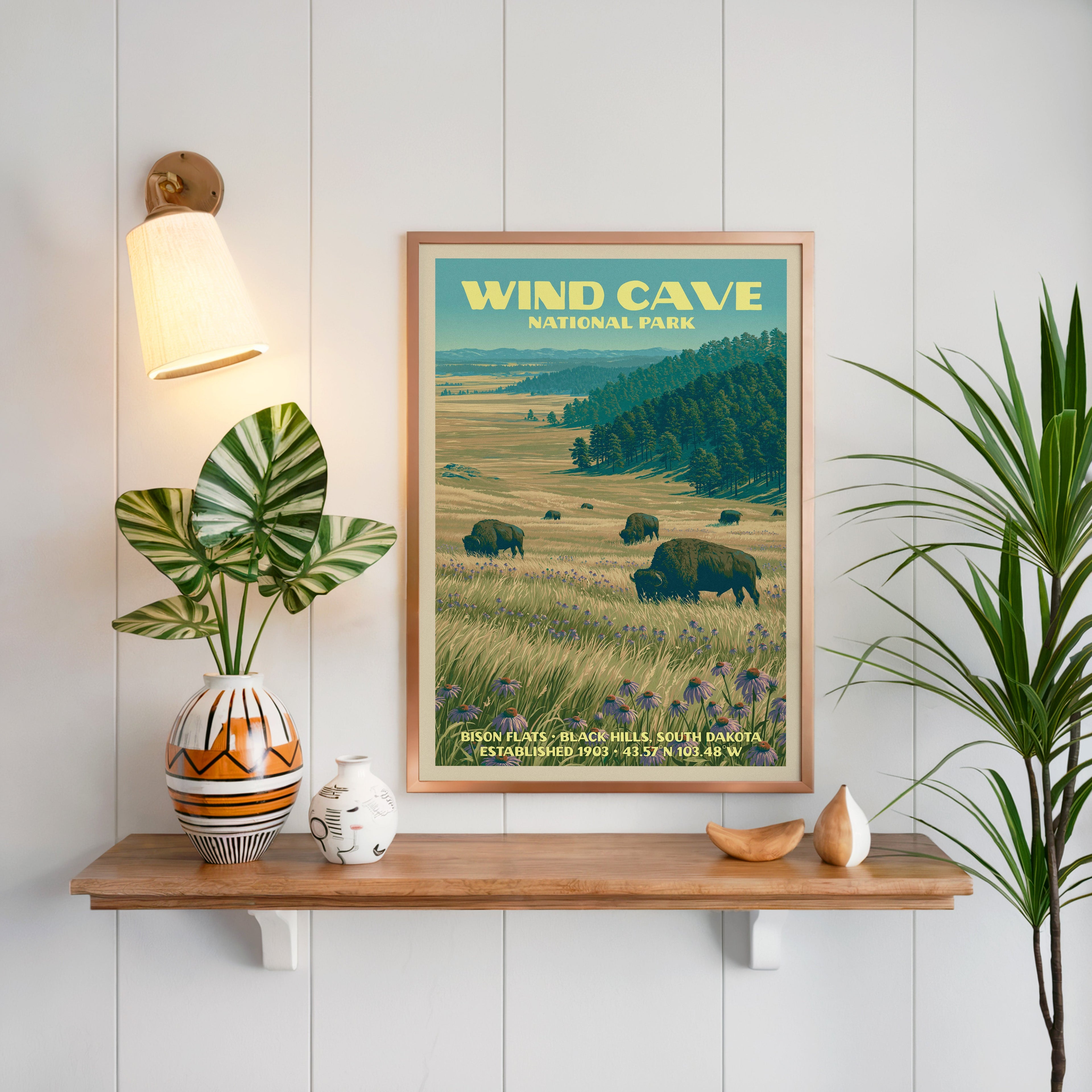 Bison Flats print framed in oak on white panelling above a floating shelf with a patterned vase and sconce