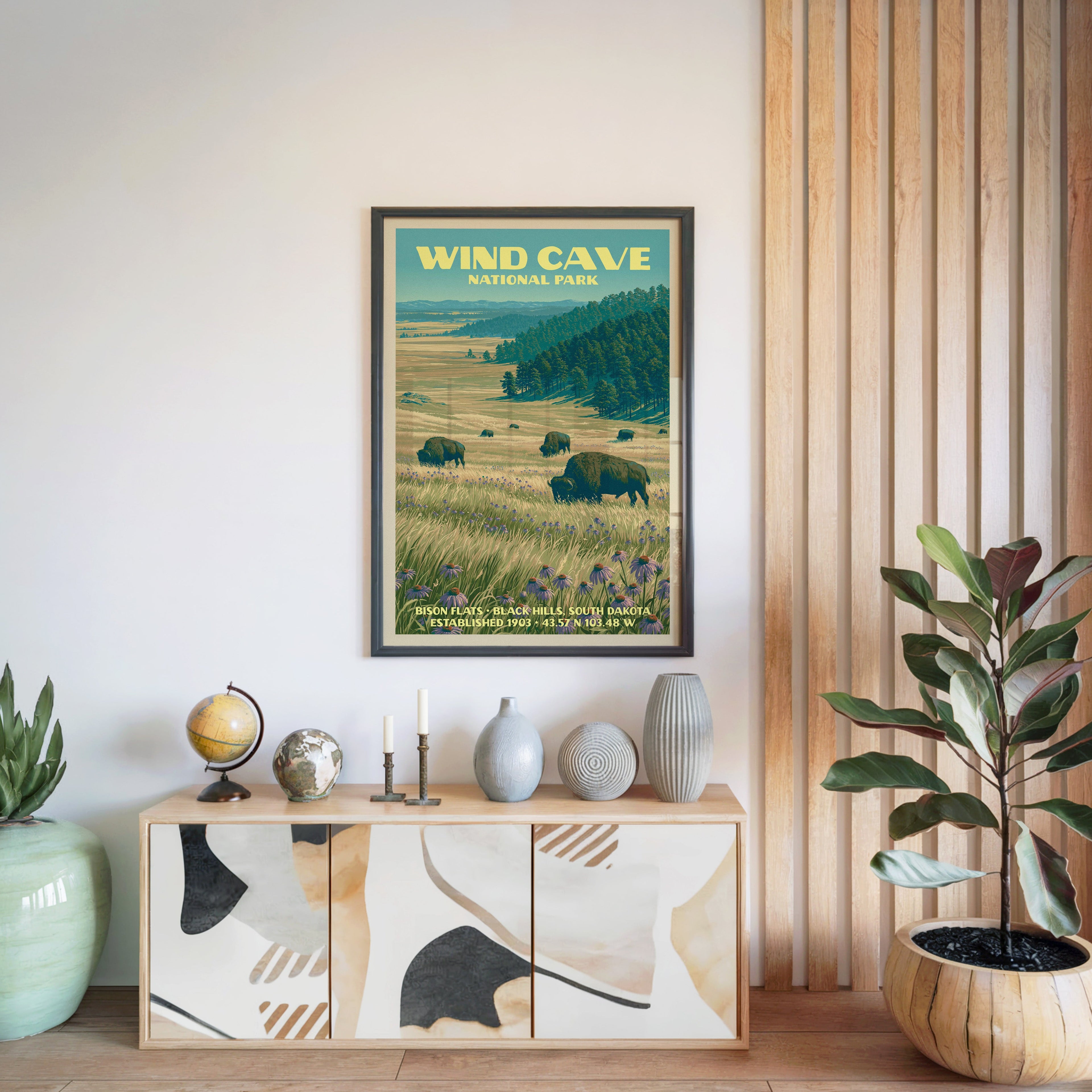 Wind Cave National Park poster in a black frame above a light wood sideboard beside a slatted wall panel