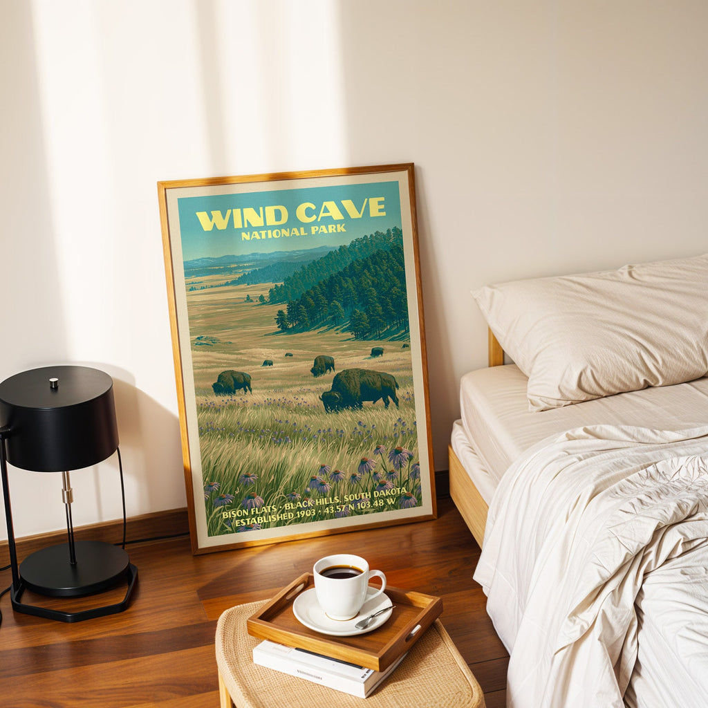 Bison Flats poster in a gold frame on the bedroom floor beside a made bed and a black table lamp