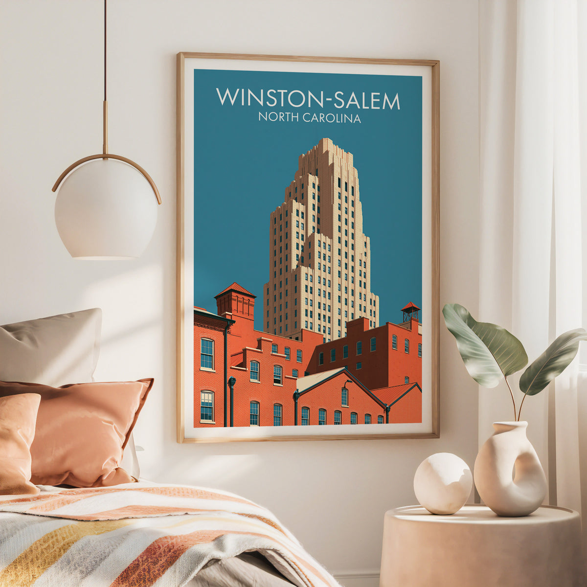 Large oak framed Winston-Salem artwork above a rust-toned bed with brass pendant lamp and side table.