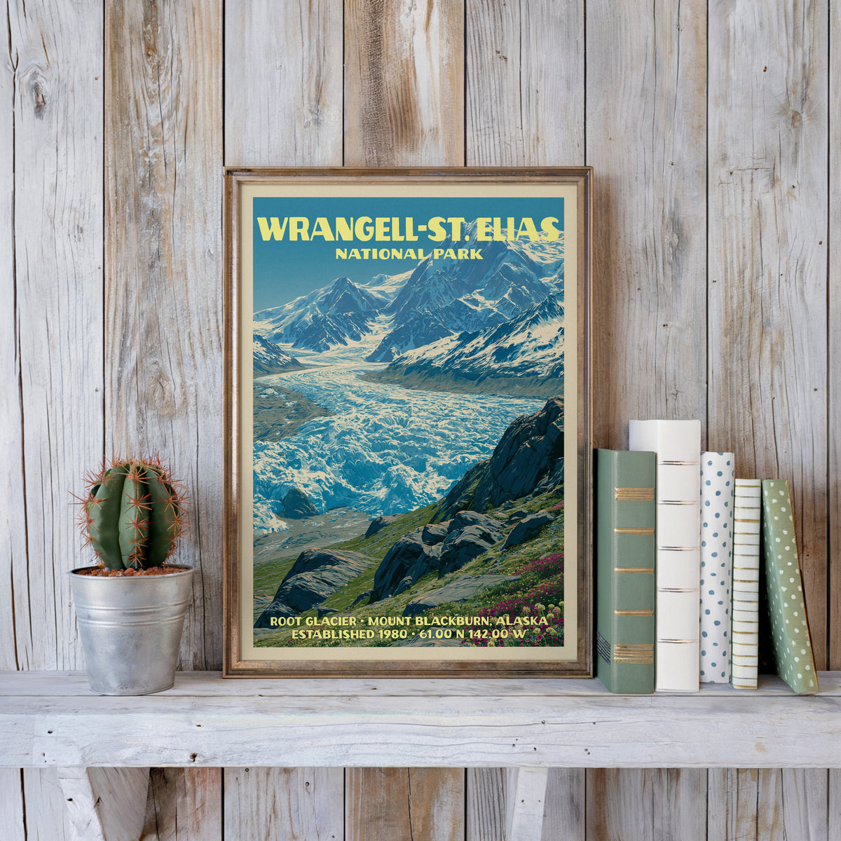 Wrangell–St. Elias vintage poster in a slim gold frame on a whitewashed plank wall beside a cactus and pastel books