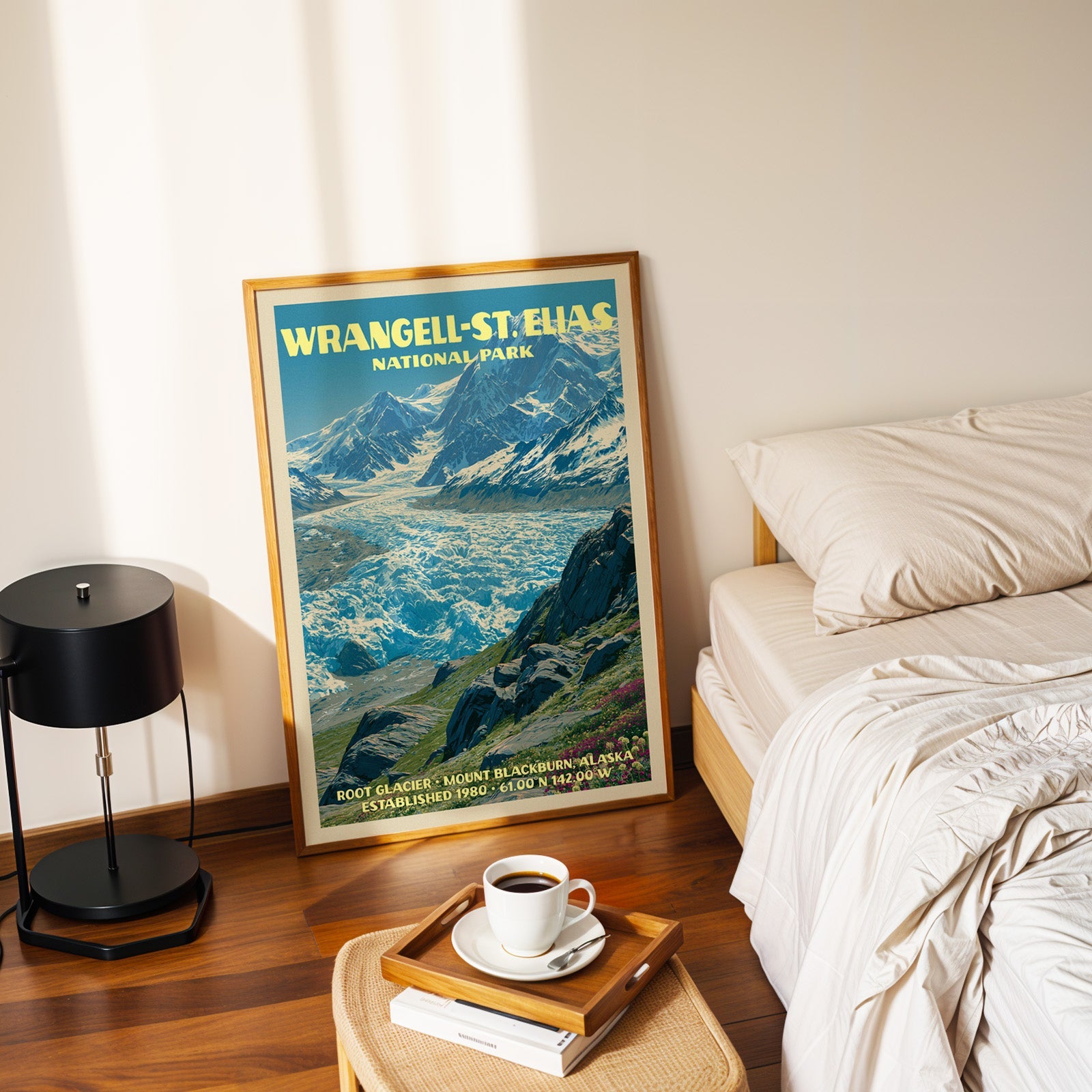 Root Glacier poster in a gold frame on the bedroom floor beside a made bed and a black table lamp
