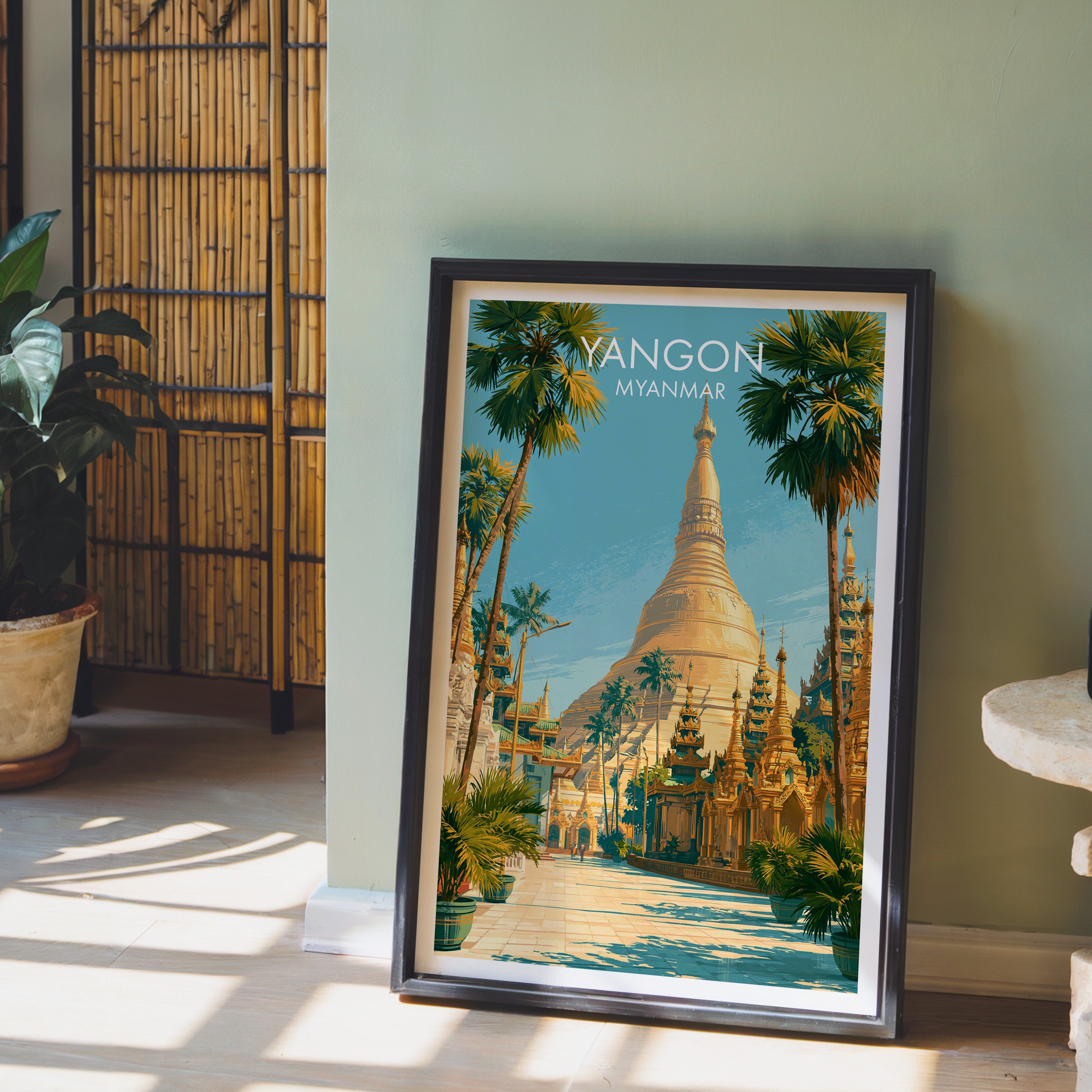 Yangon Myanmar wall art in a black frame leaning against a sage green wall beside a bamboo screen
