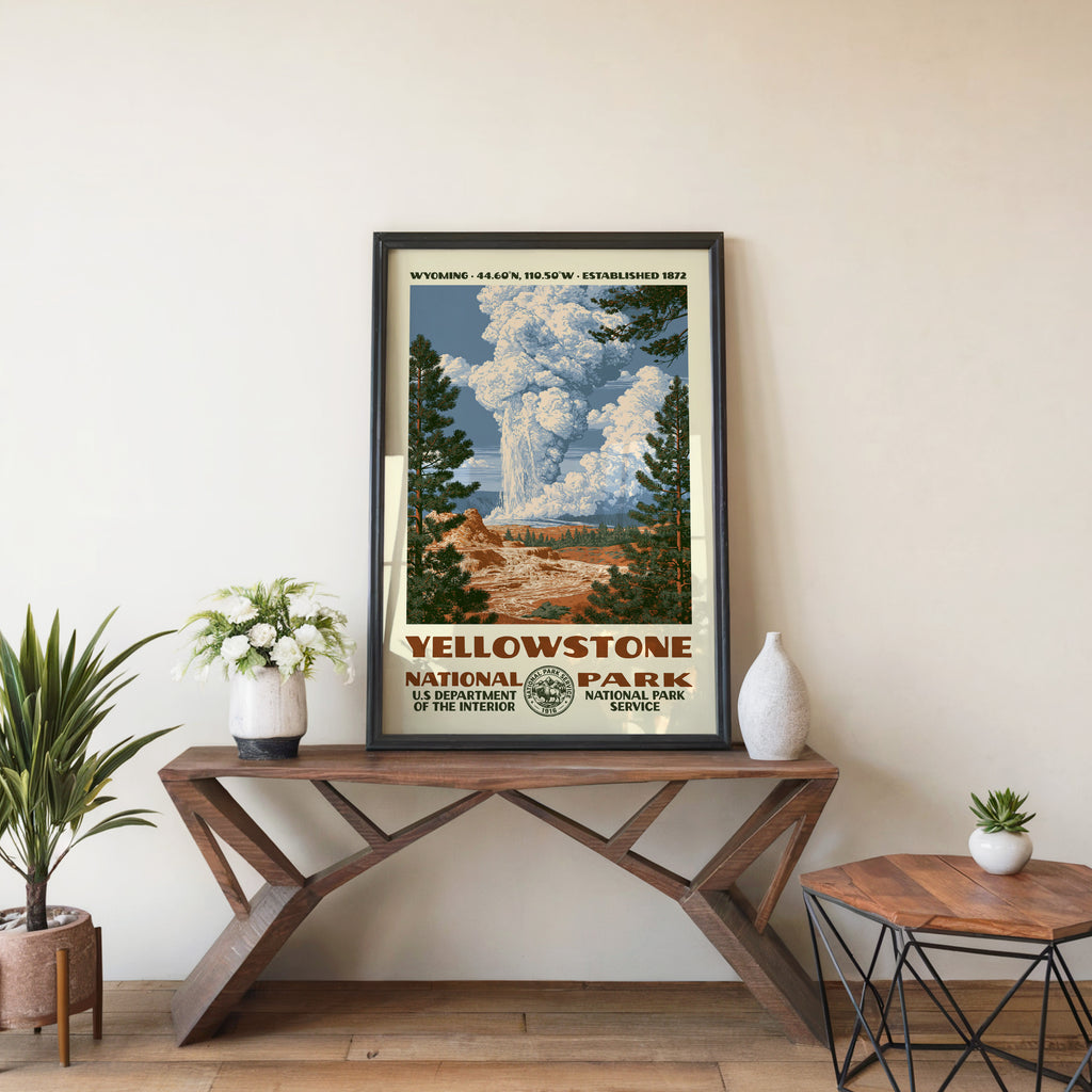 Yellowstone National Park travel poster in a black frame on a wood console table with houseplants