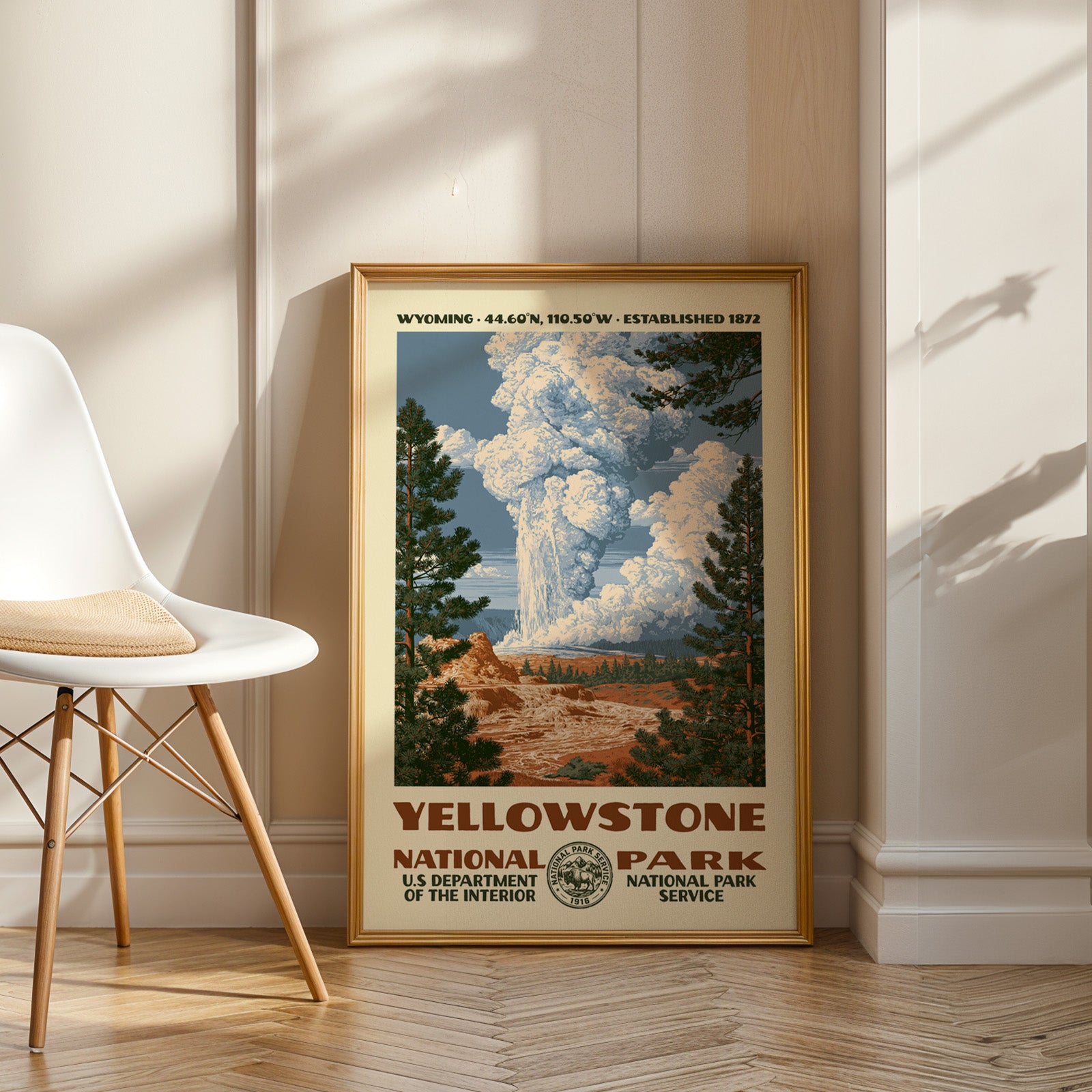 Yellowstone National Park vintage WPA art in an oak frame leaning by a white chair on a wood floor