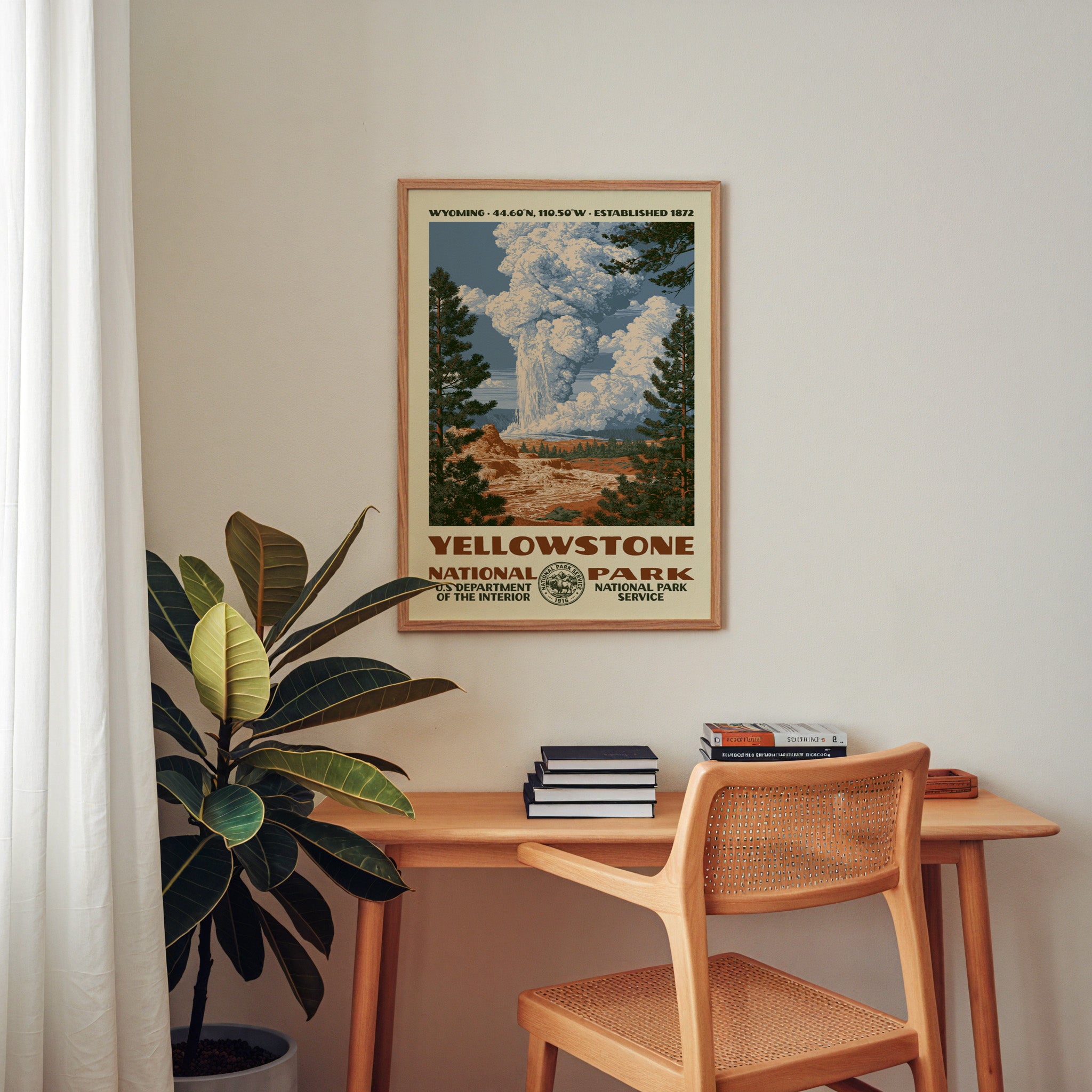 Yellowstone National Park retro poster framed above a wooden home office desk with books and plants